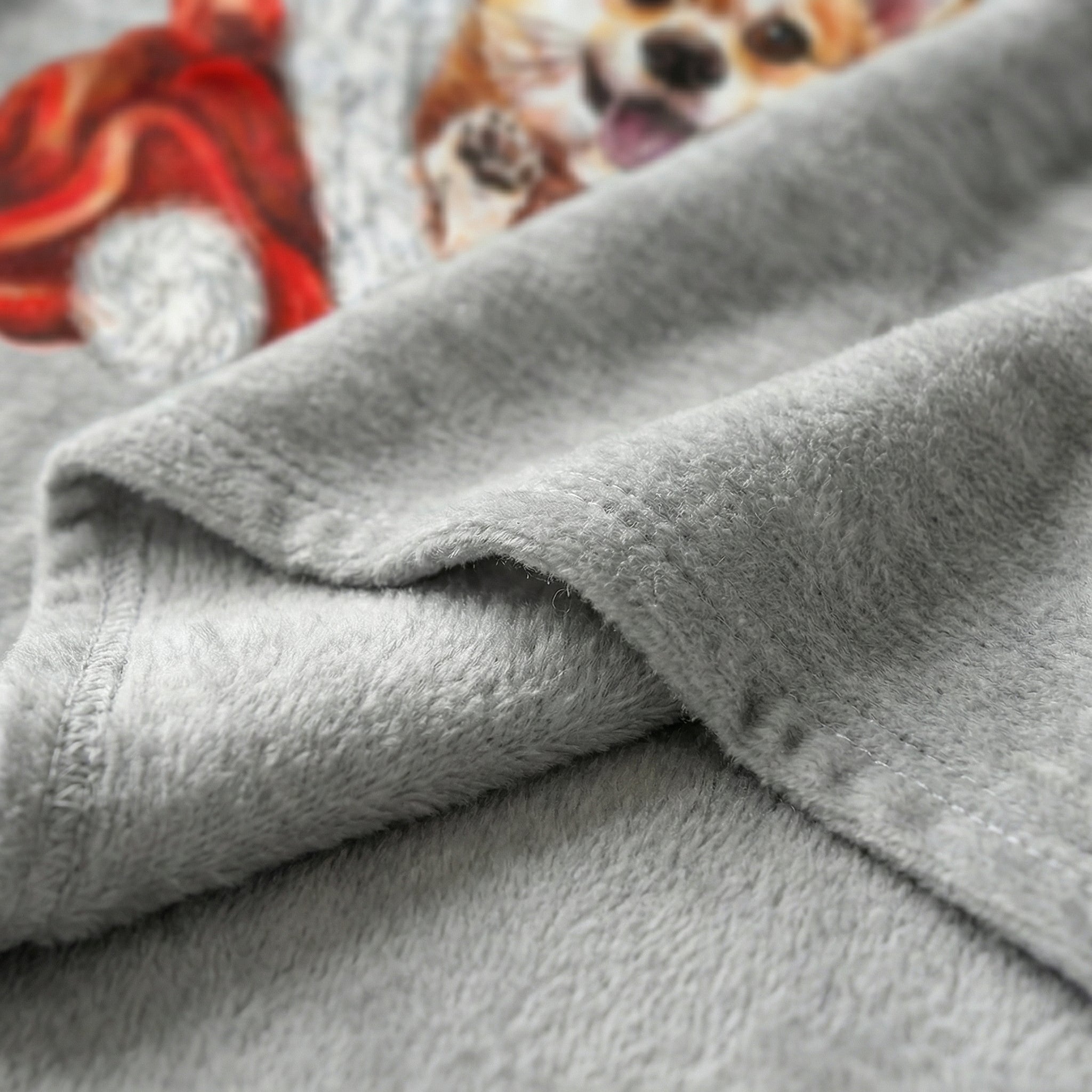 Close-up of a soft, gray flannel blanket with a playful Corgi print and a red winter hat.