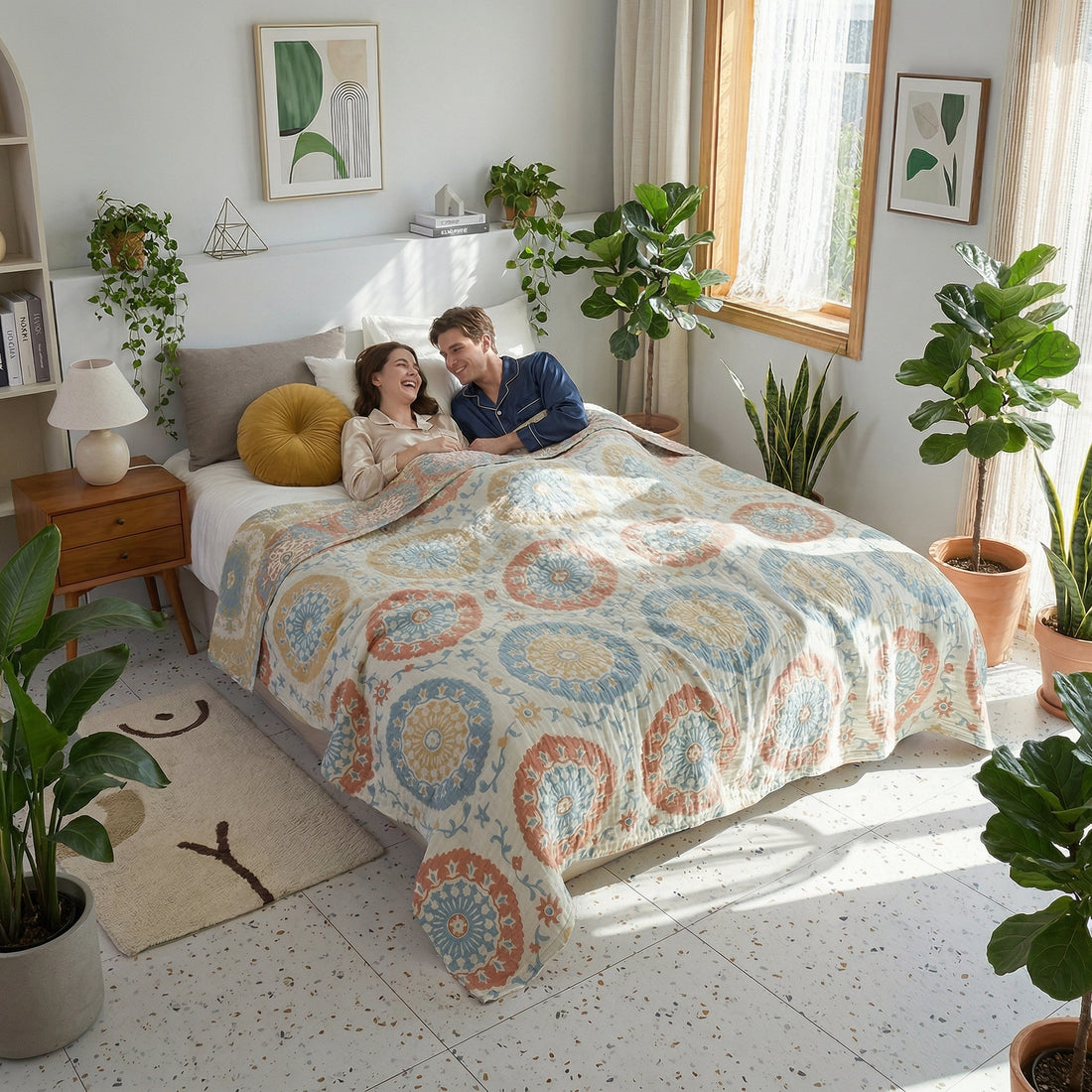 Couple relaxing in bed under a light blue, orange, and yellow patterned cotton gauze blanket.