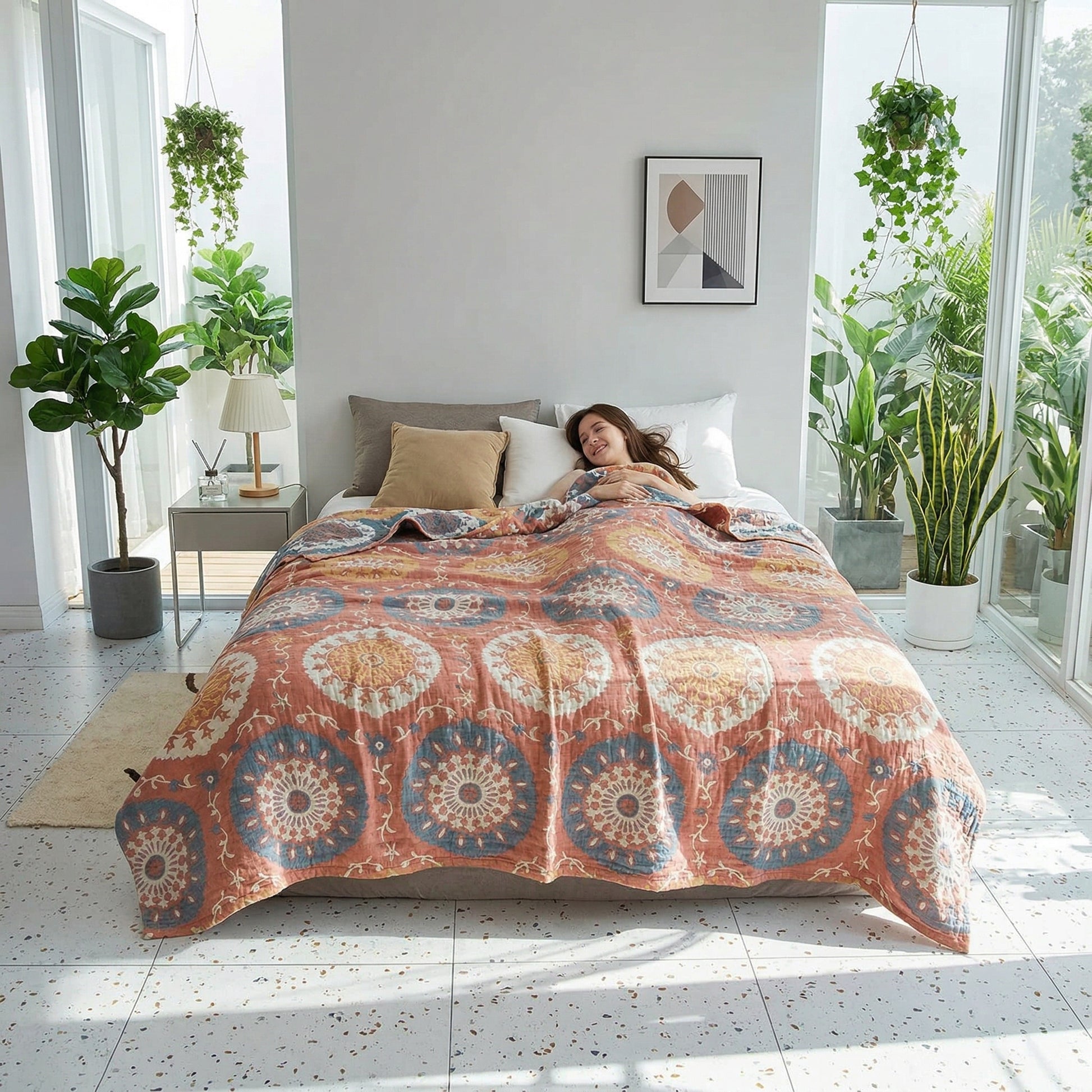 Woman sleeping under a terracotta cotton gauze summer blanket with blue and gold jacquard patterns.