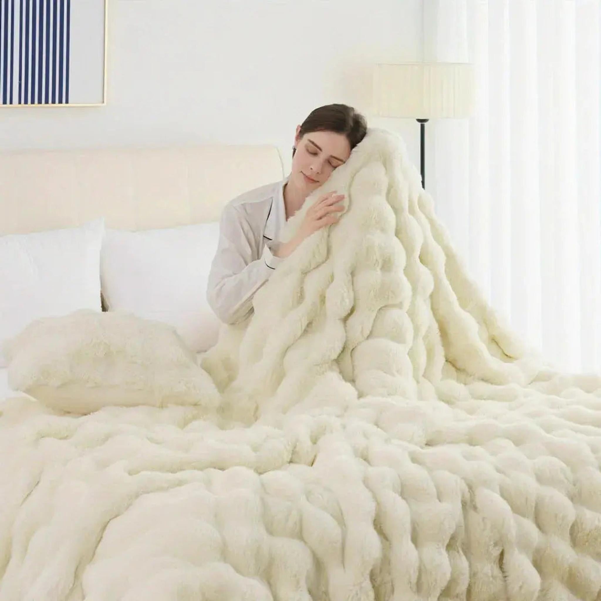 Woman sleeping peacefully under a plush, cream faux rabbit fleece throw blanket with a textured design.