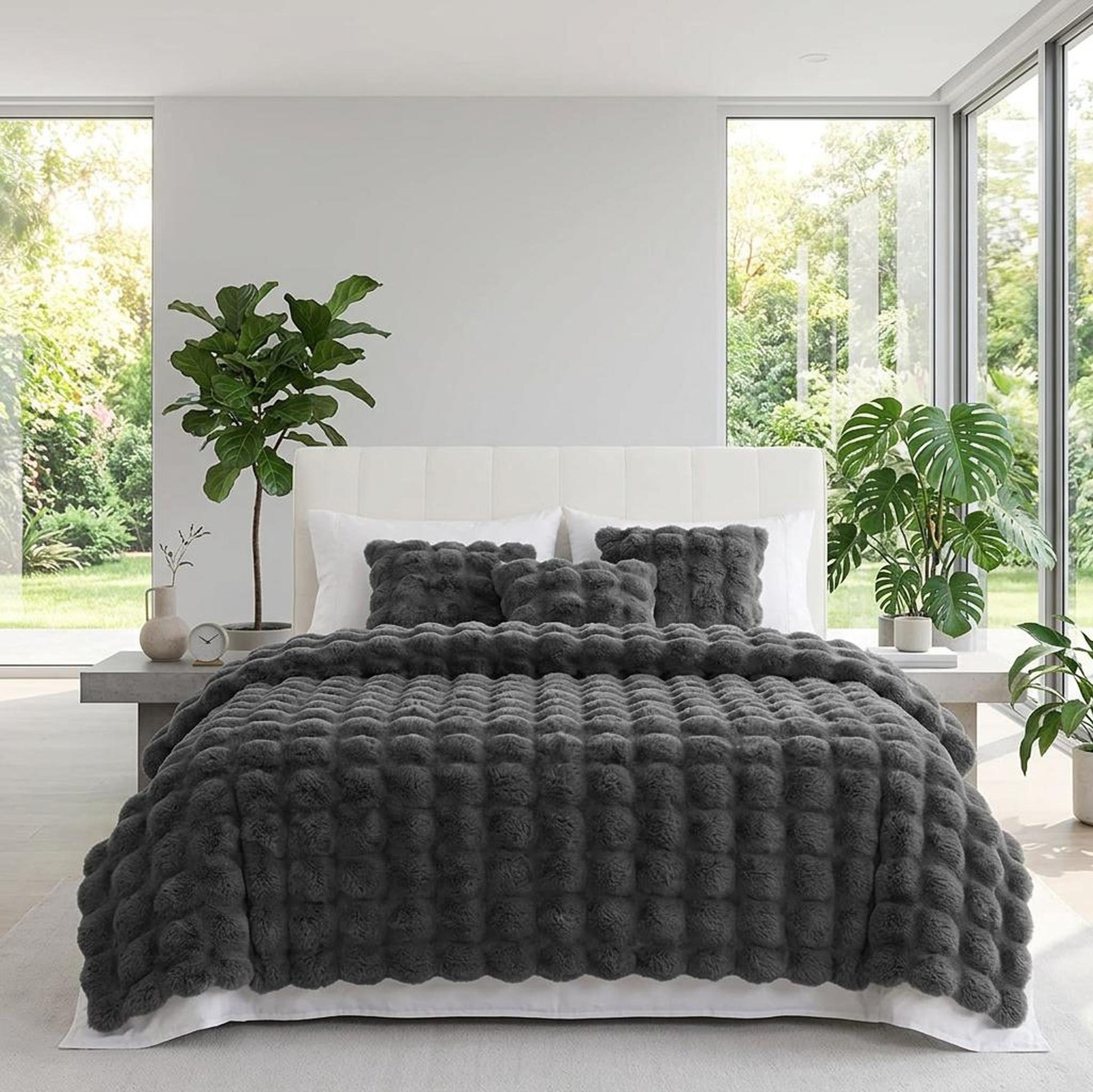 Dark gray faux rabbit fleece throw blanket with textured bobbles on a bed with matching pillows.