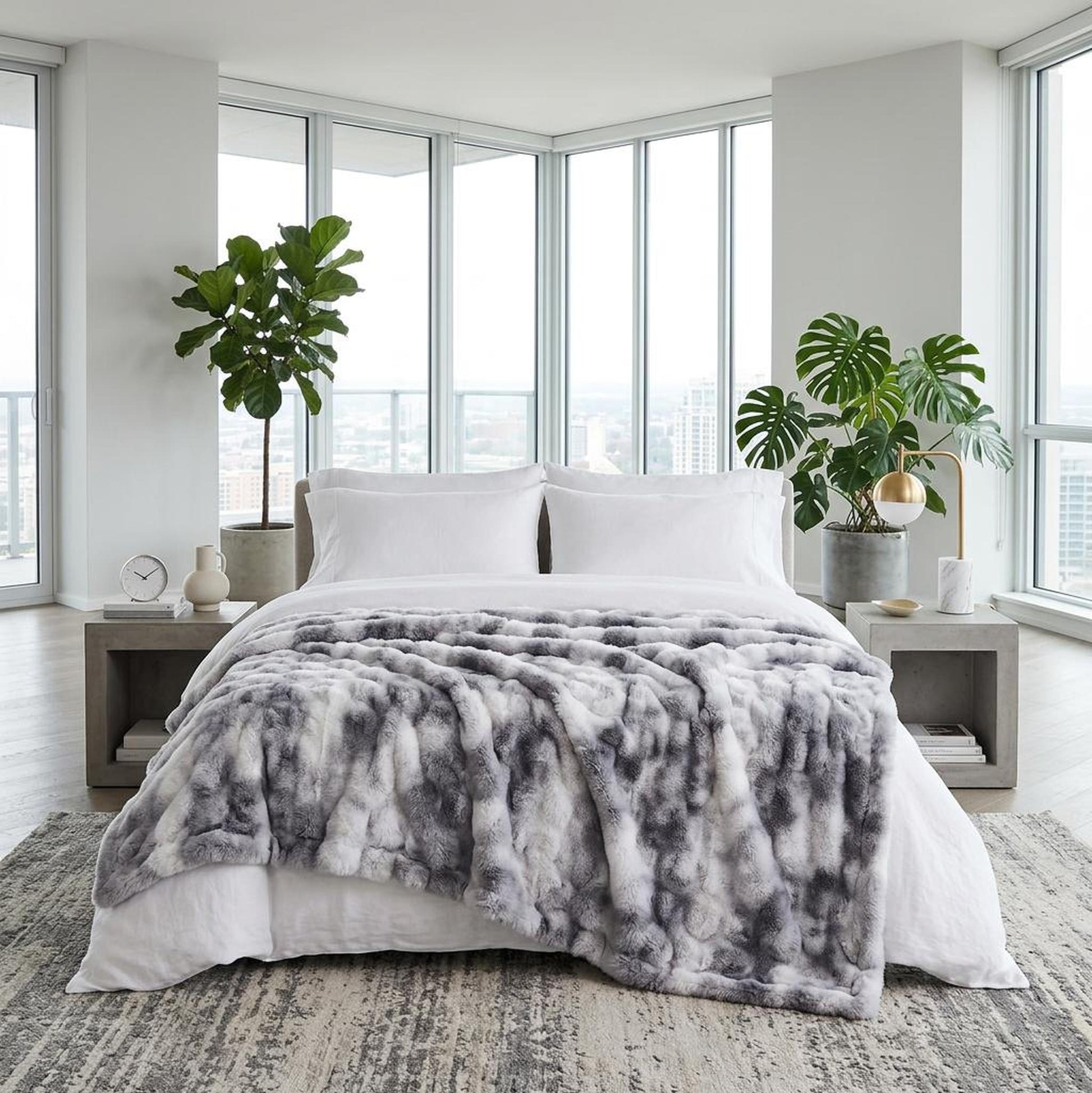 Gray and white faux rabbit fleece throw blanket draped on a bed in a modern bedroom.