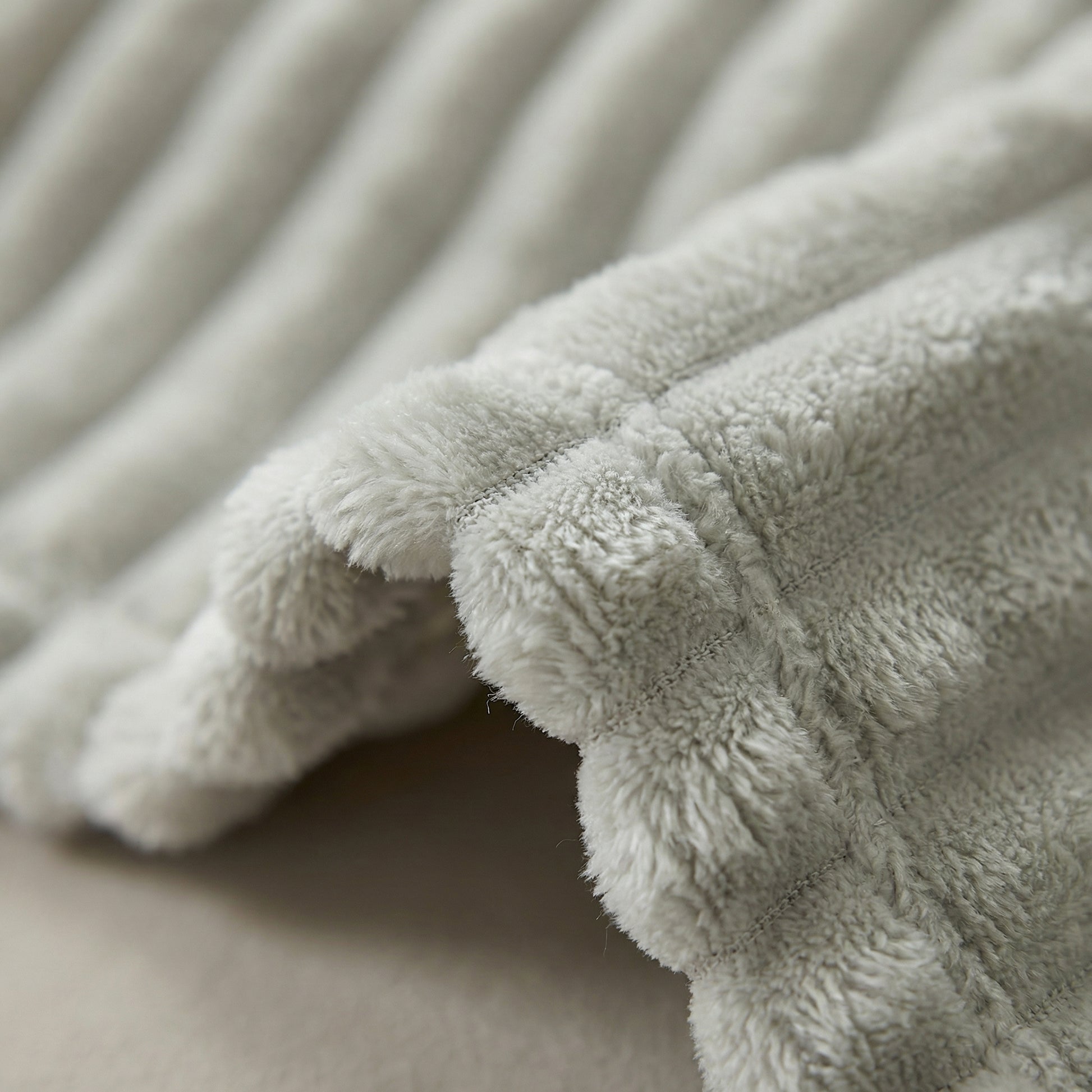 Close-up of a soft, light gray CozySoft Double-Sided Blanket with plush, ribbed texture and visible stitching.