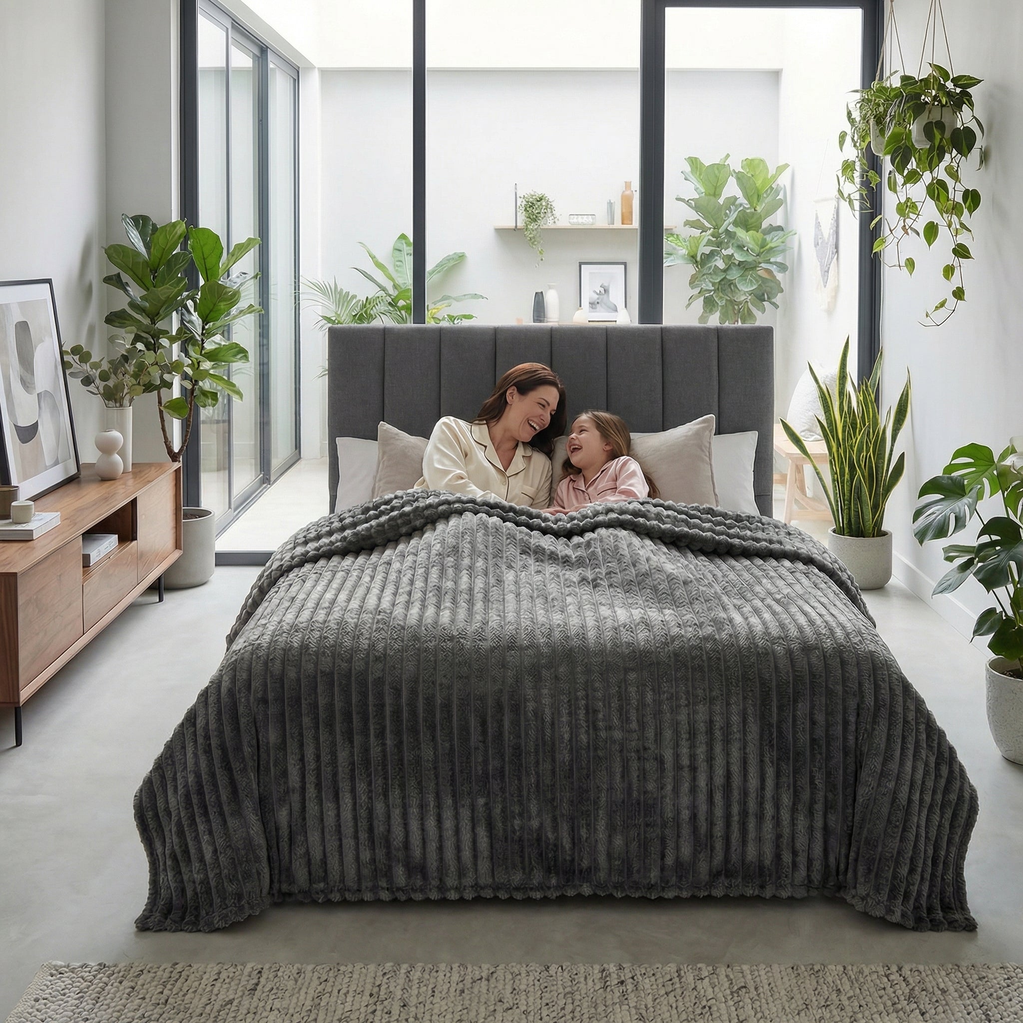 CozySoft Double-Sided Blanket in dark grey plush, covering a bed where a mother and child relax.