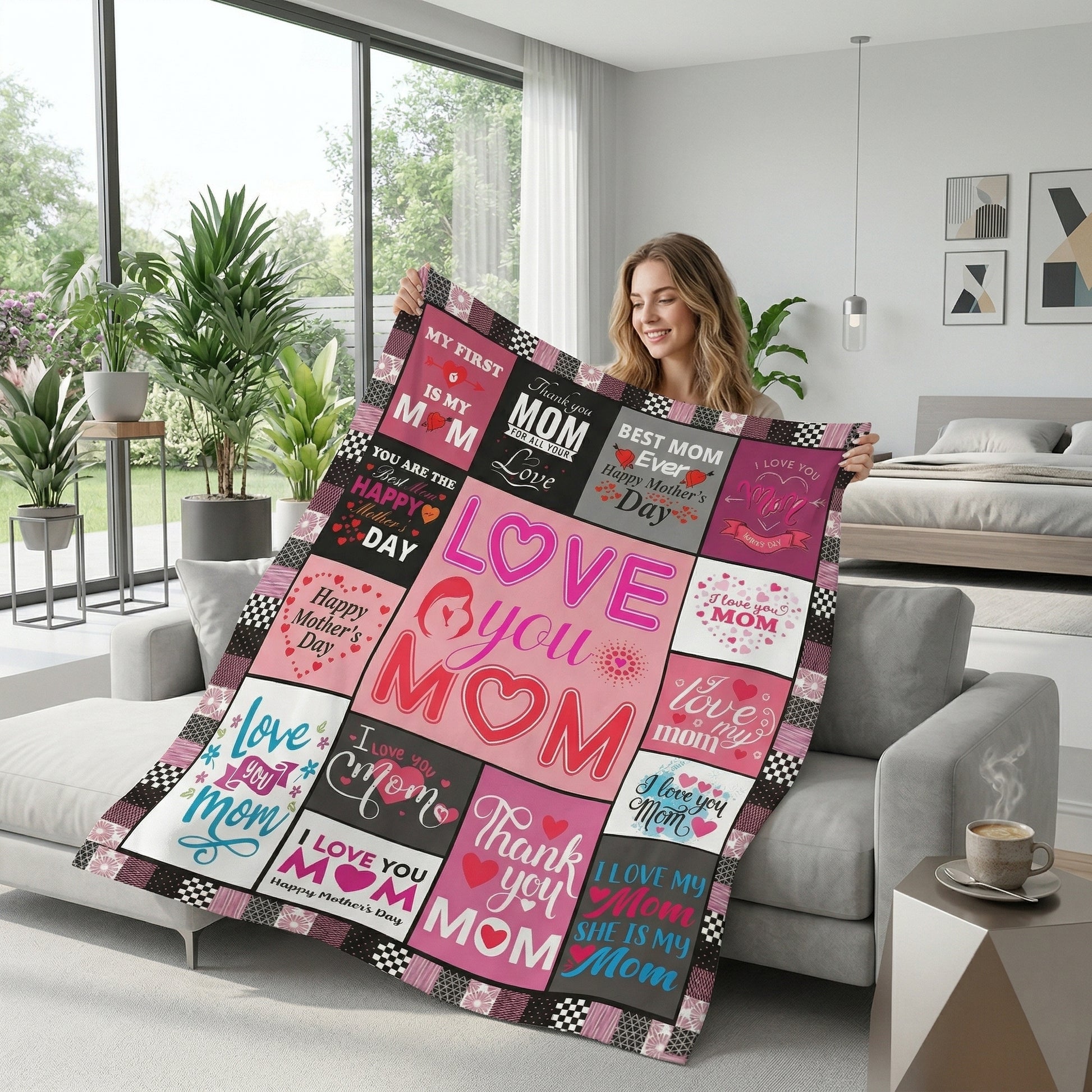 Smiling woman holding a pink and black "Love You Mom" flannel throw blanket with checkered accents in a modern living room.