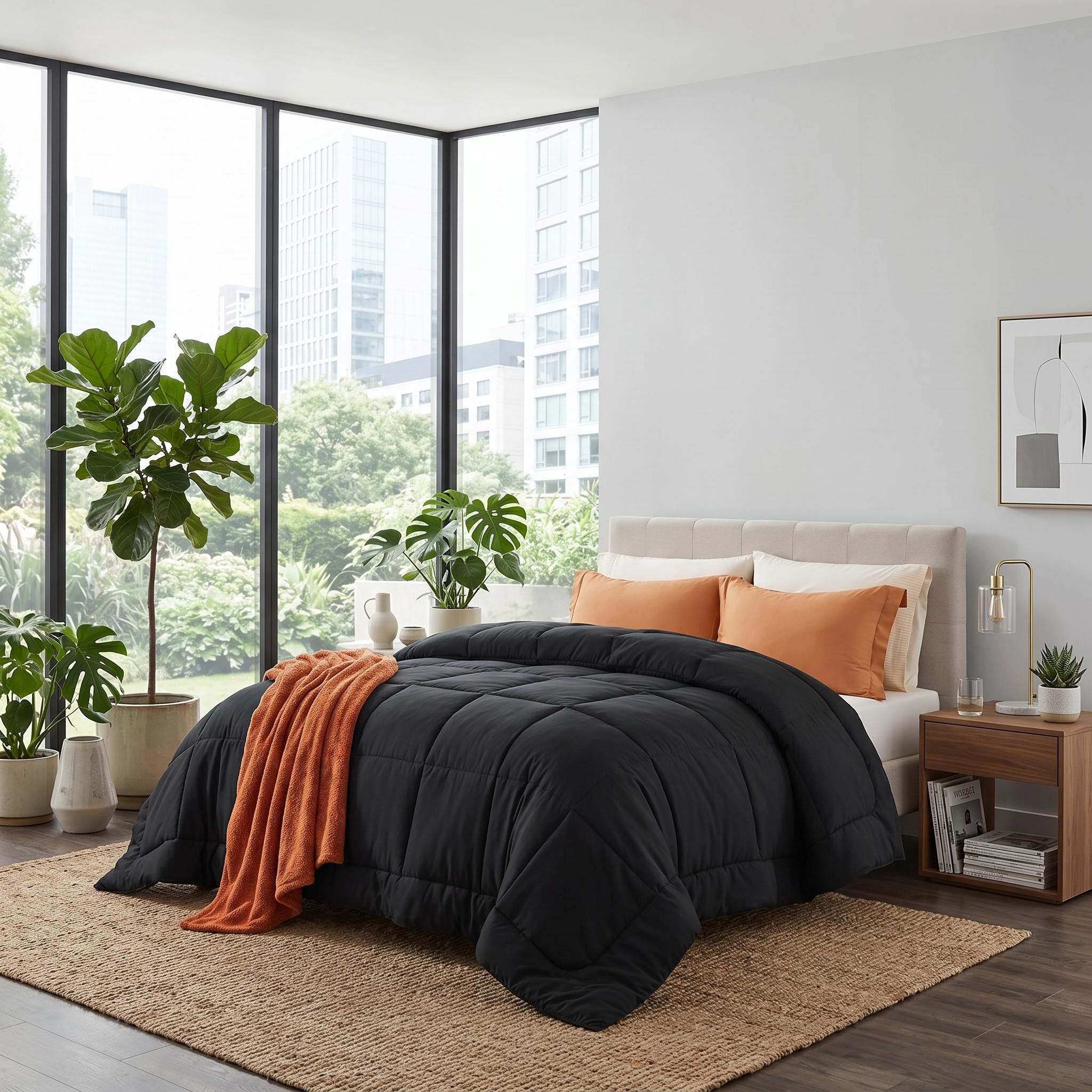 Black down alternative comforter with box stitch design, orange throw, and pillows on a bed in a modern bedroom.