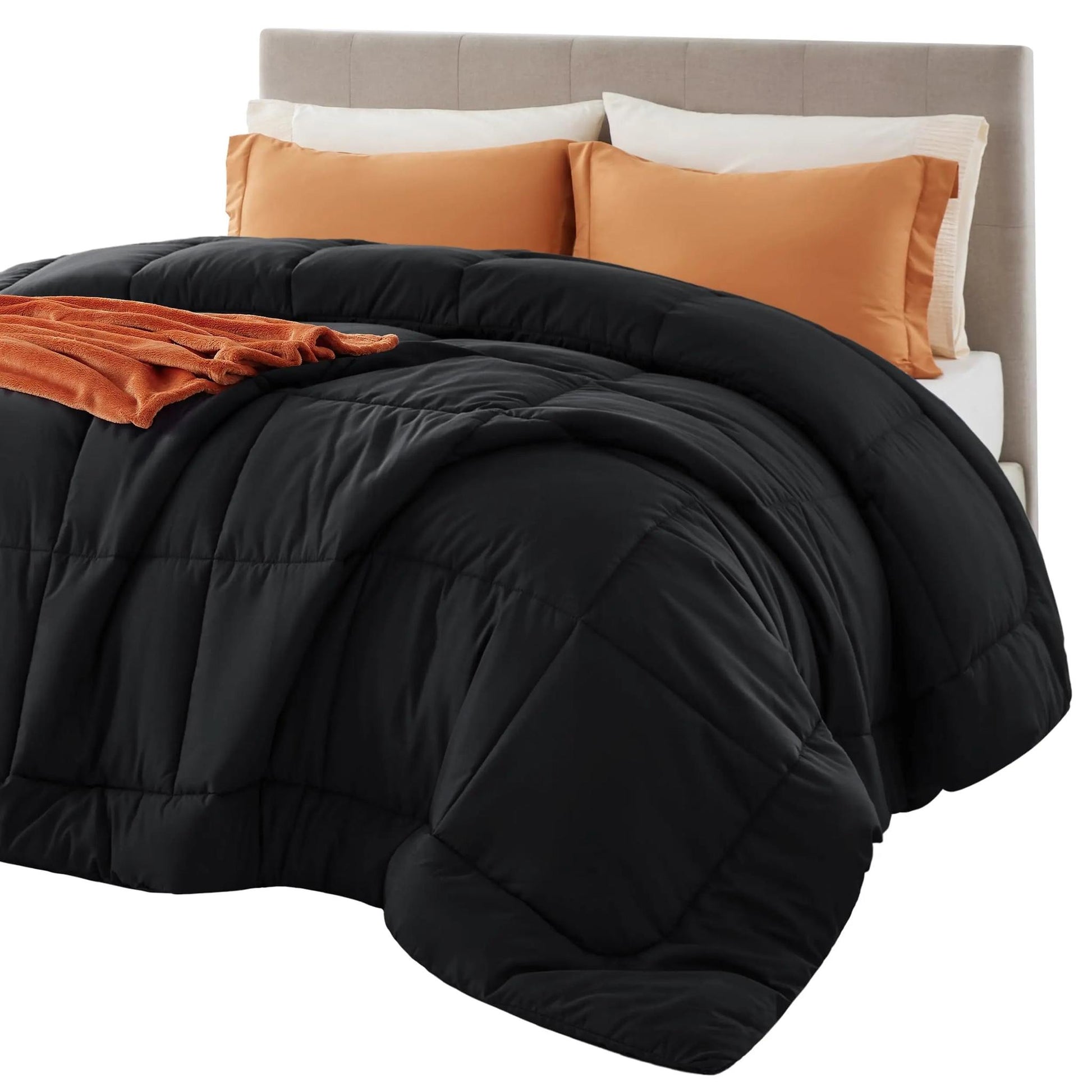 Black down alternative comforter with box stitch design on a bed with orange pillows and throw.