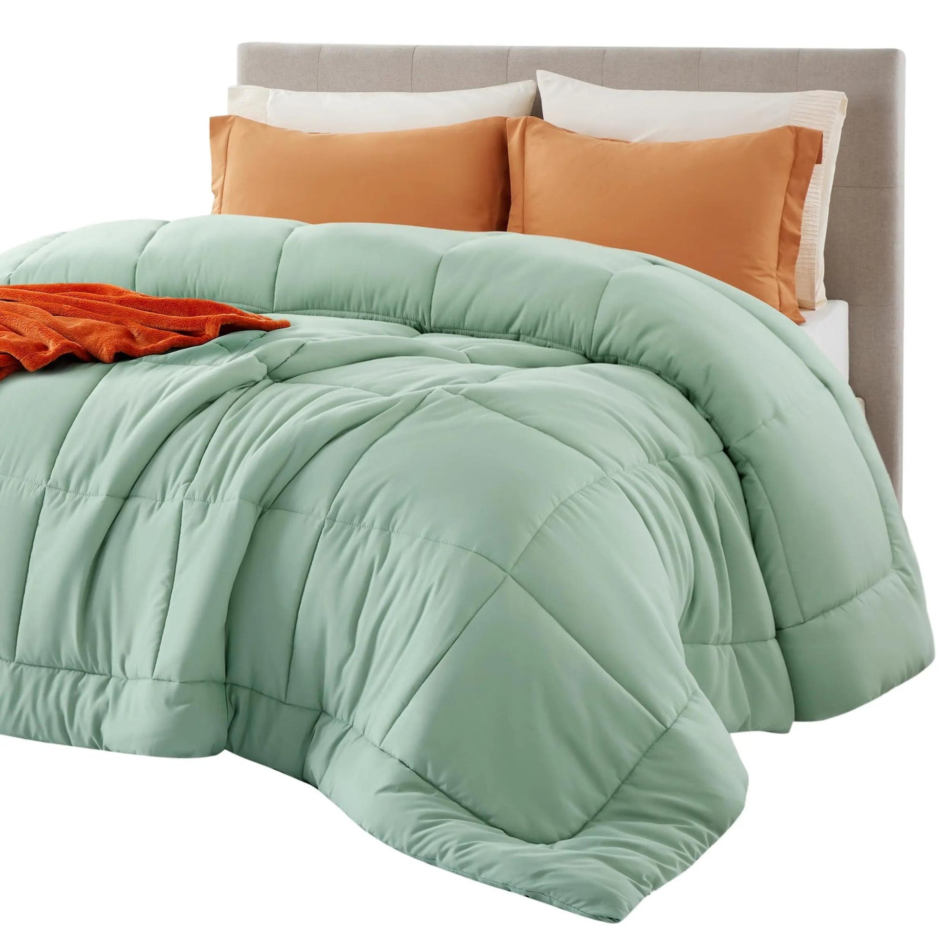 Light green down alternative comforter with box stitch design on a bed with orange pillows and throw.
