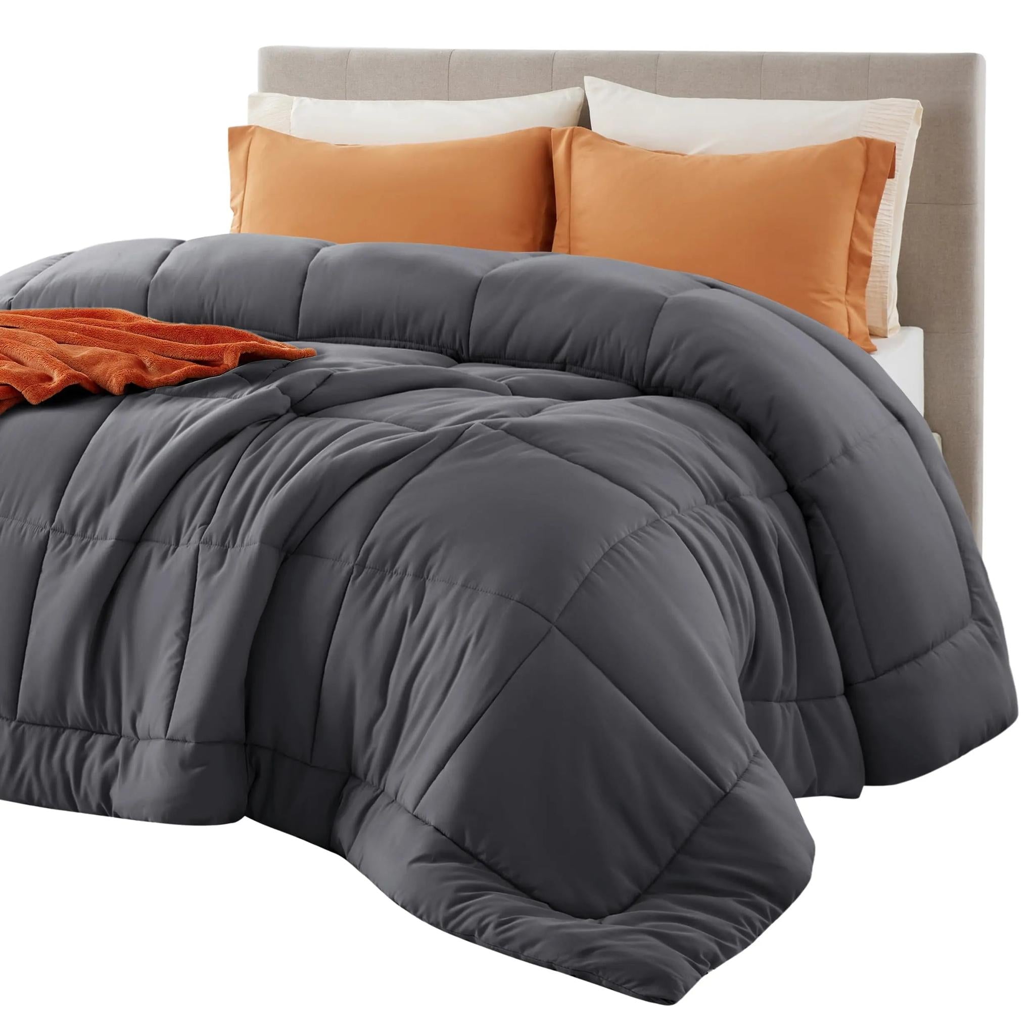Dark gray down alternative comforter with box stitch design on a bed with orange pillows.