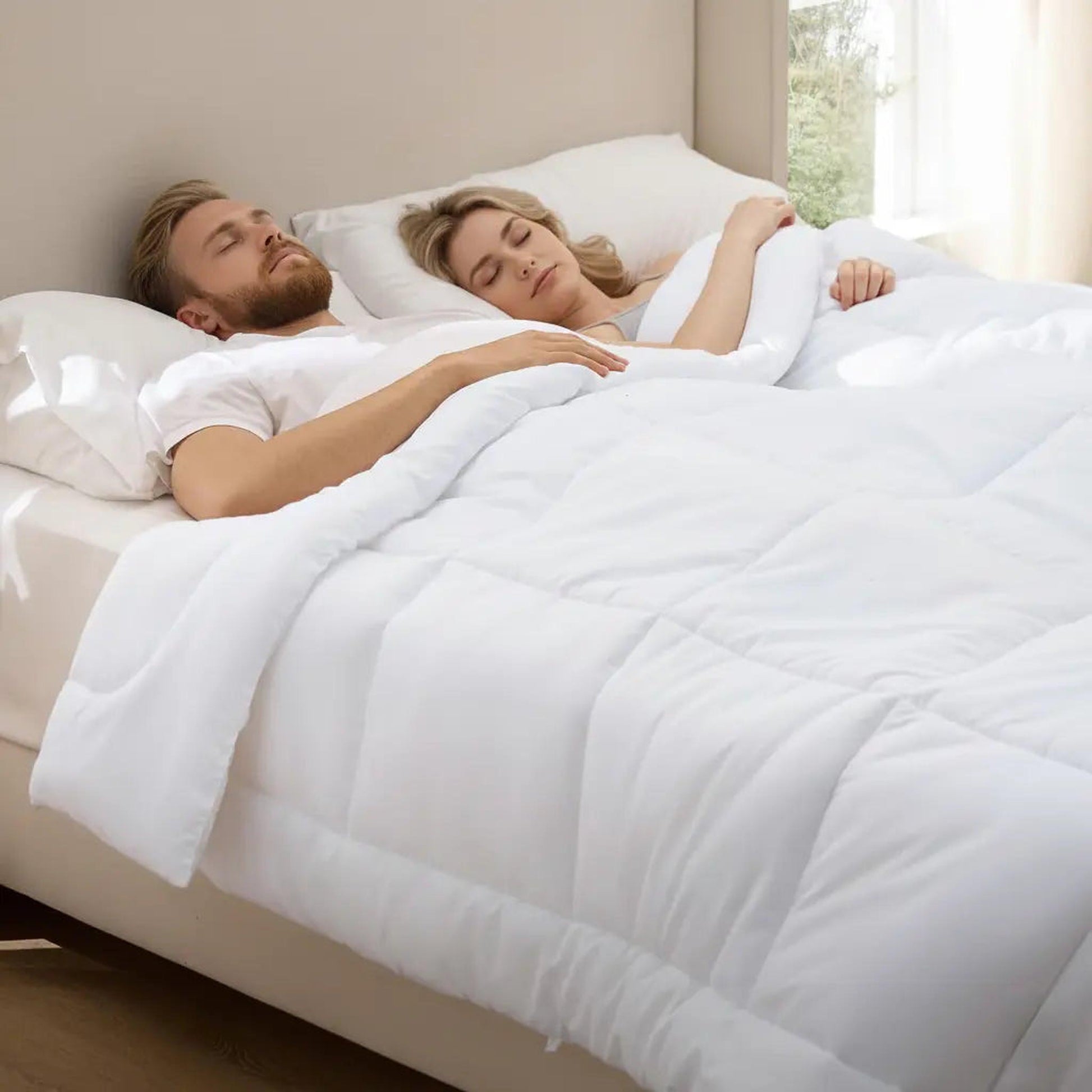 Couple sleeping soundly under a white, lightweight box stitch down alternative comforter.