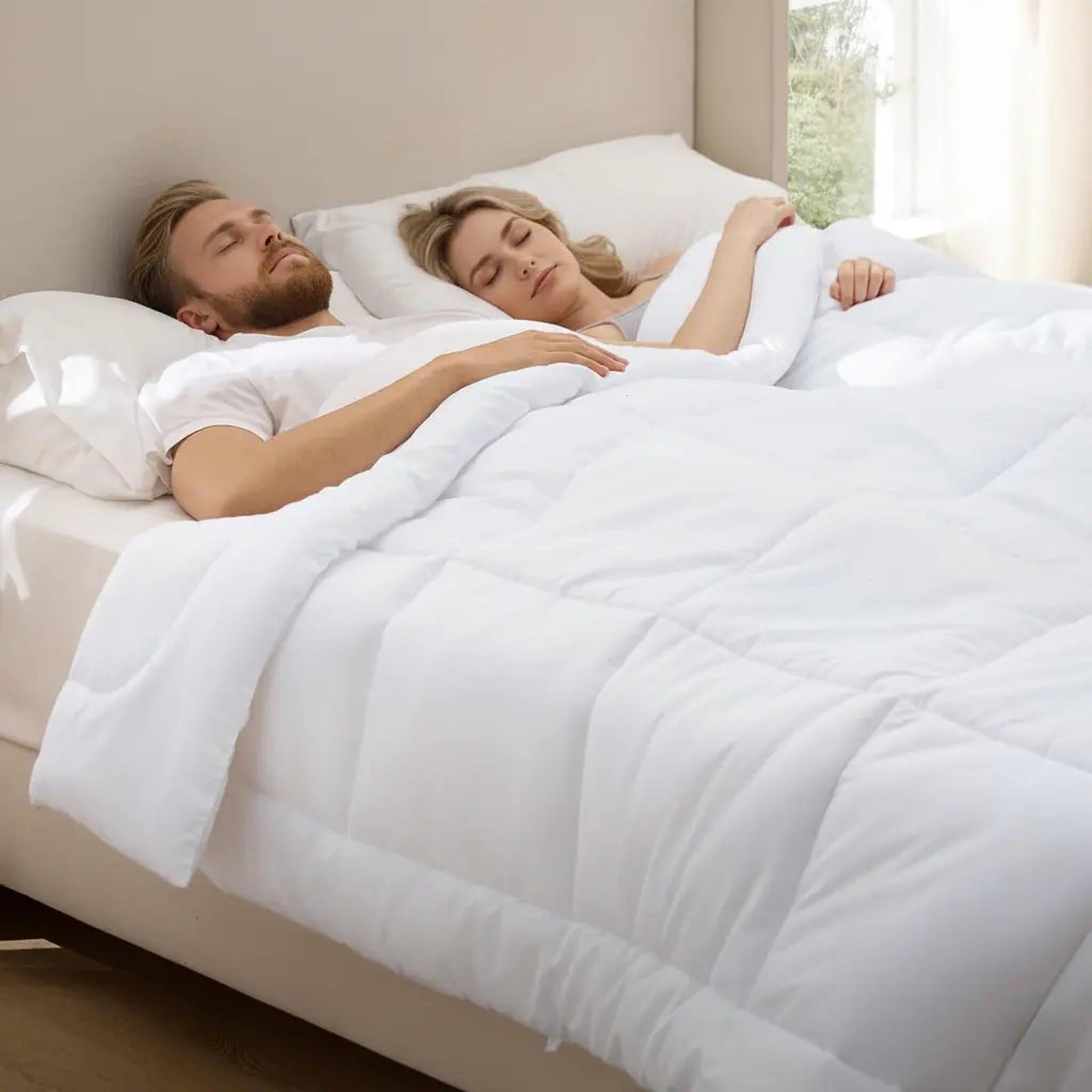 Couple sleeping soundly under a white, lightweight box stitch down alternative comforter.