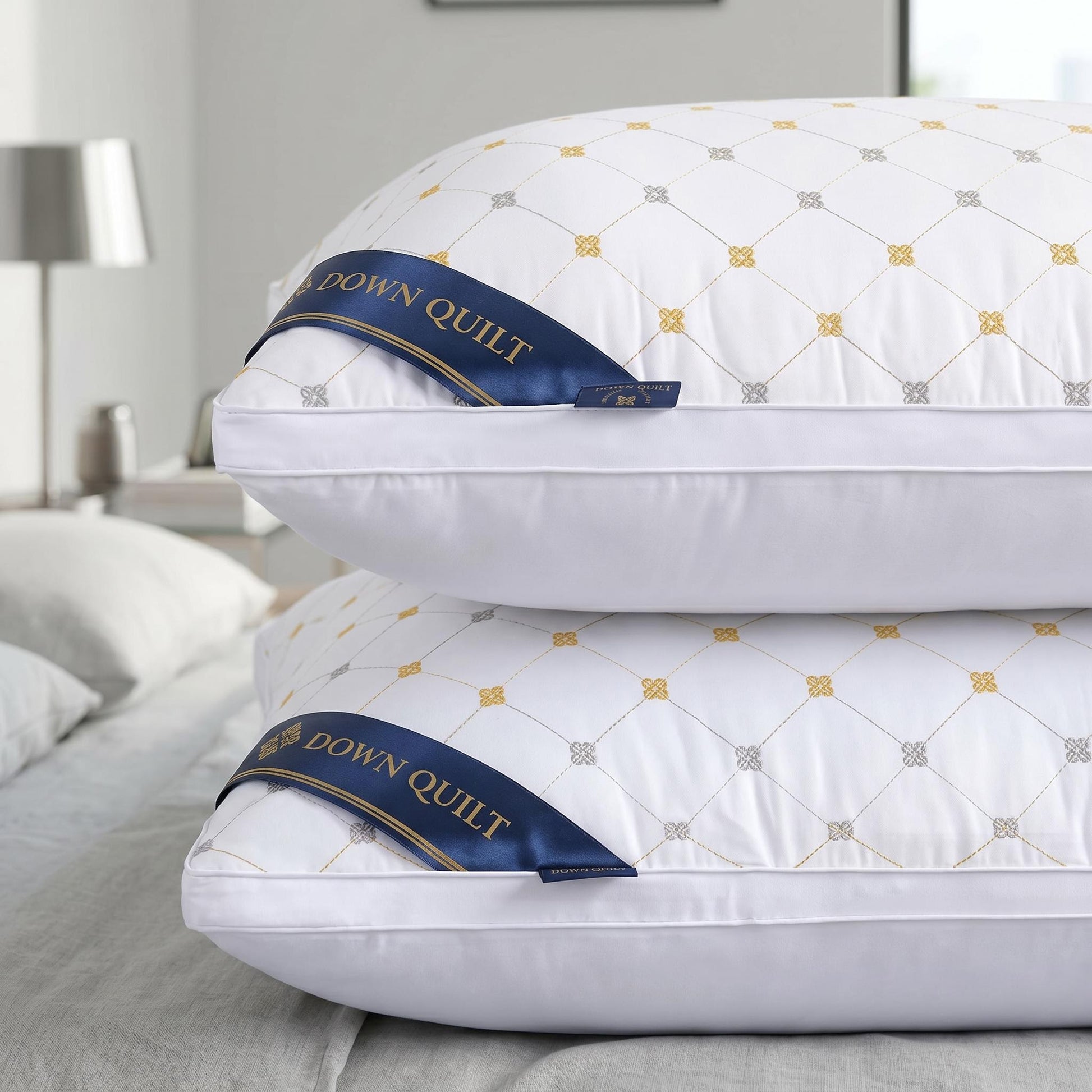 Two white queen-size down alternative pillows with quilted gold and gray patterns, stacked on a bed.
