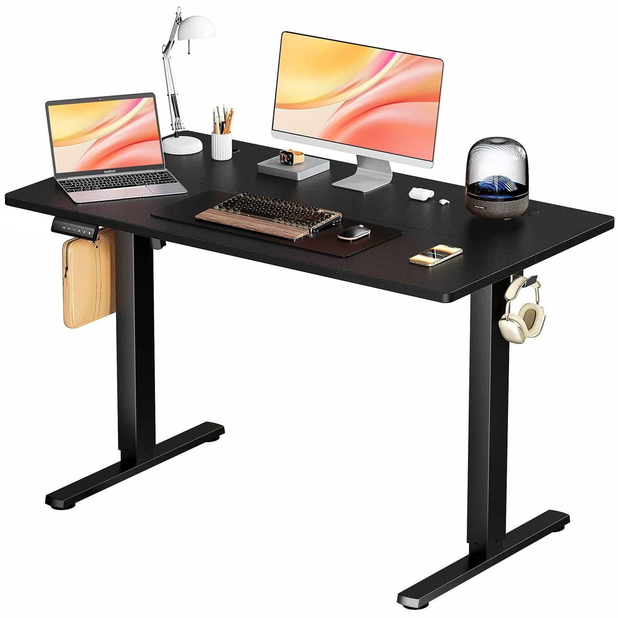 Black electric adjustable height standing desk with a laptop, monitor, and accessories.