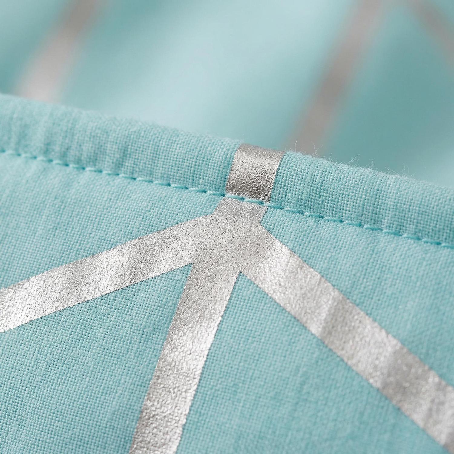 Close-up of a light blue microfiber comforter with silver geometric foil design and stitched edge.