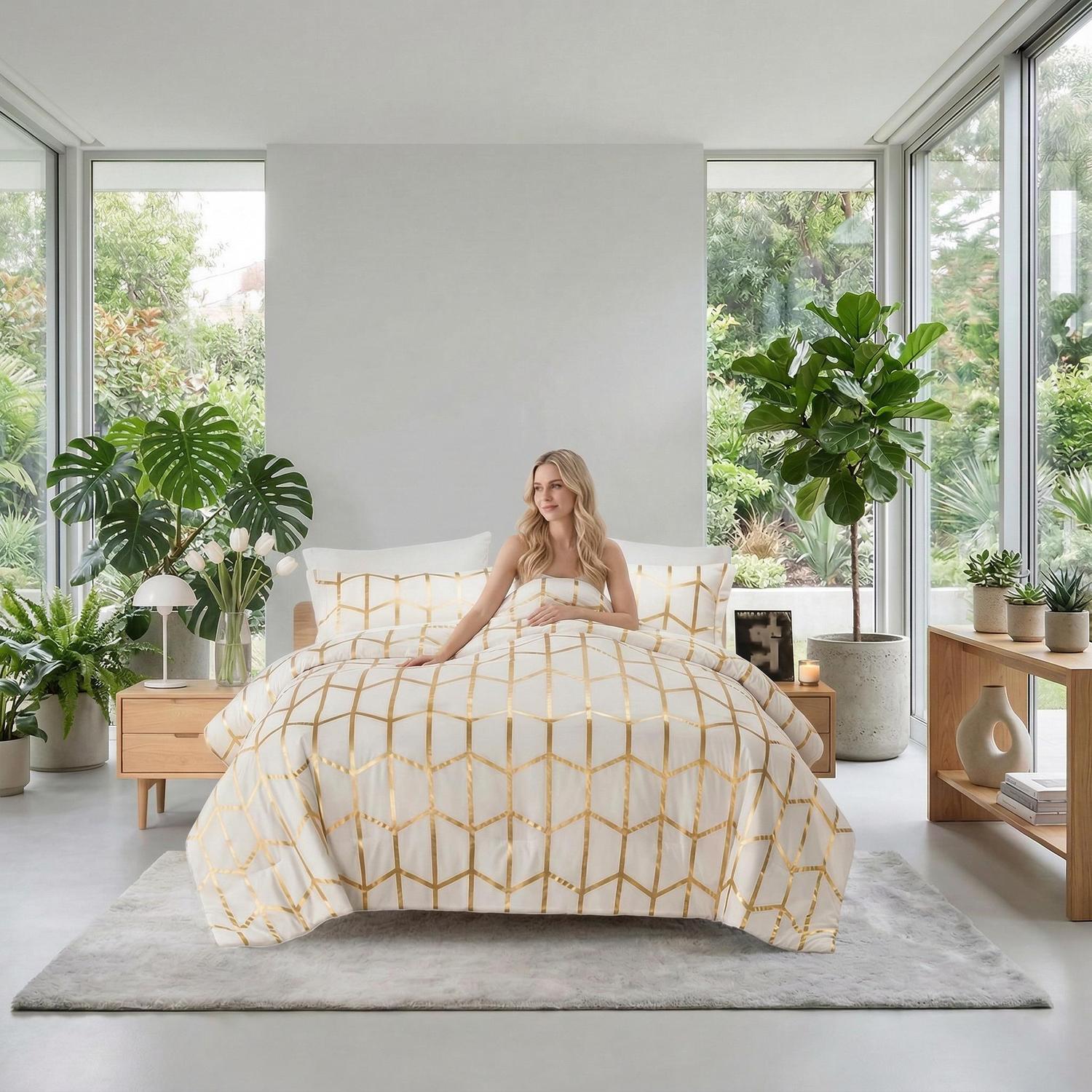 Blonde woman on a bed with an elegant white and gold geometric foil comforter set in a bright room.