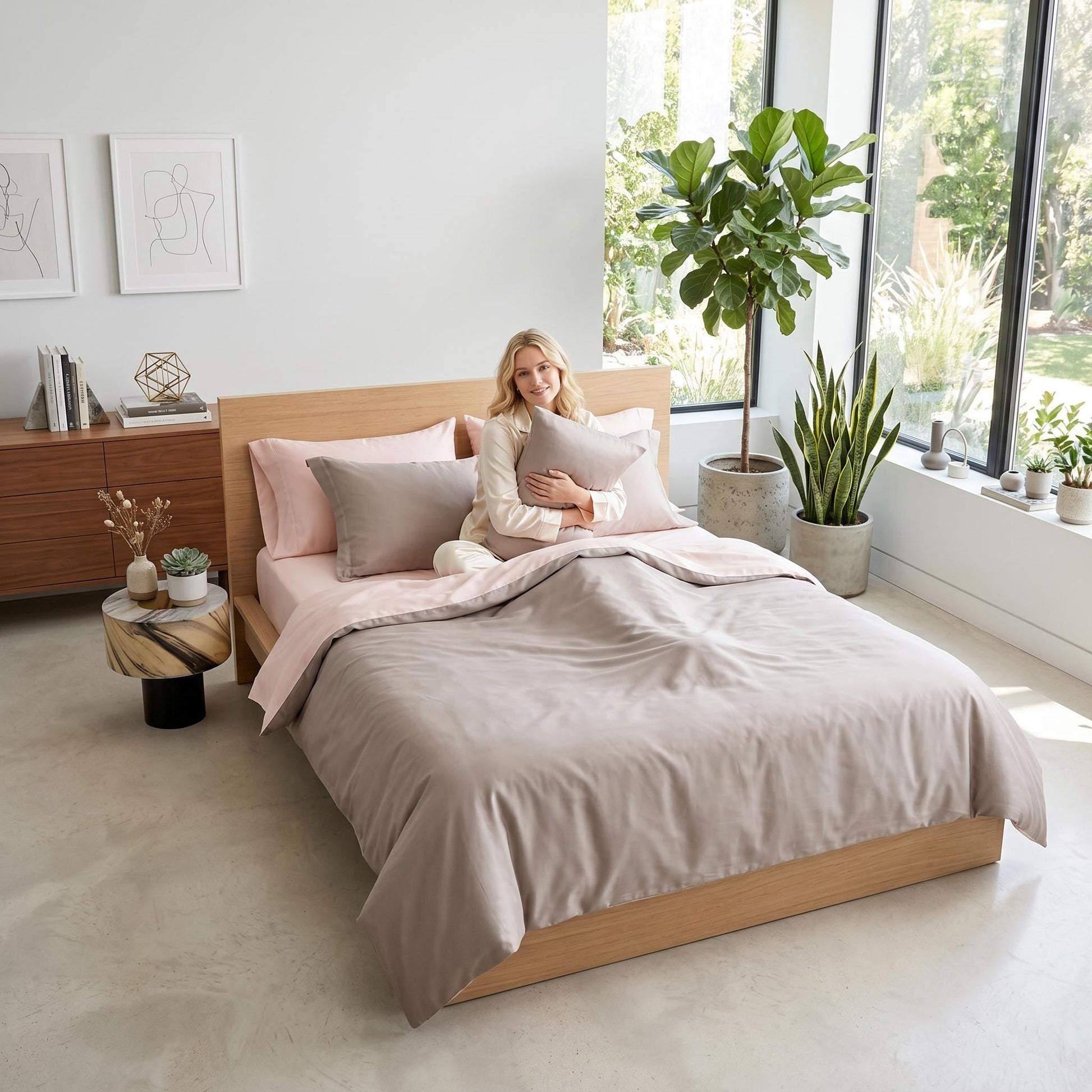 Blonde woman on a bed with elegant organic cotton bedding in blush pink and taupe, sateen weave.