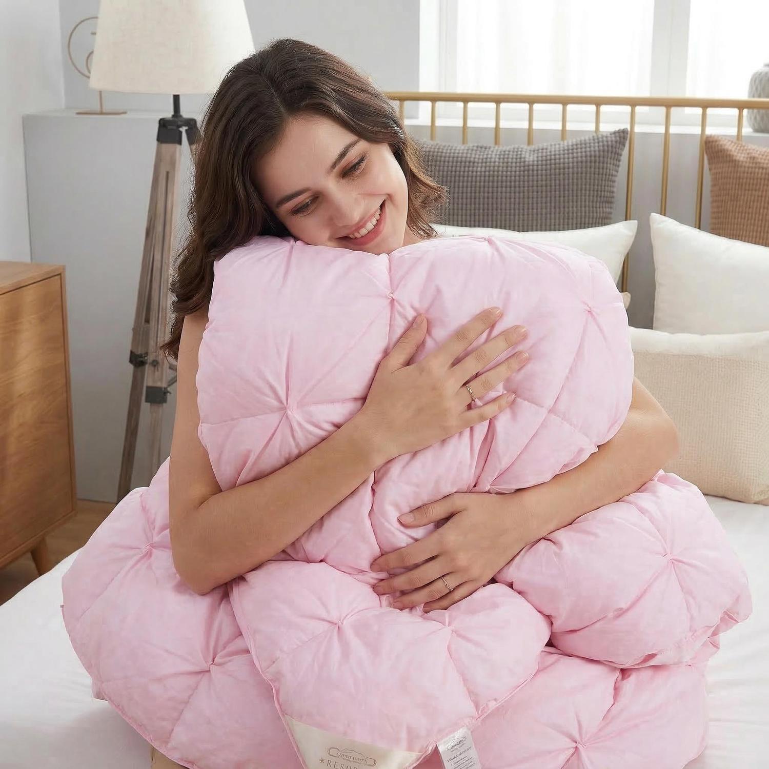 Smiling woman hugging a soft pink goose down quilt with a twist flower pattern.