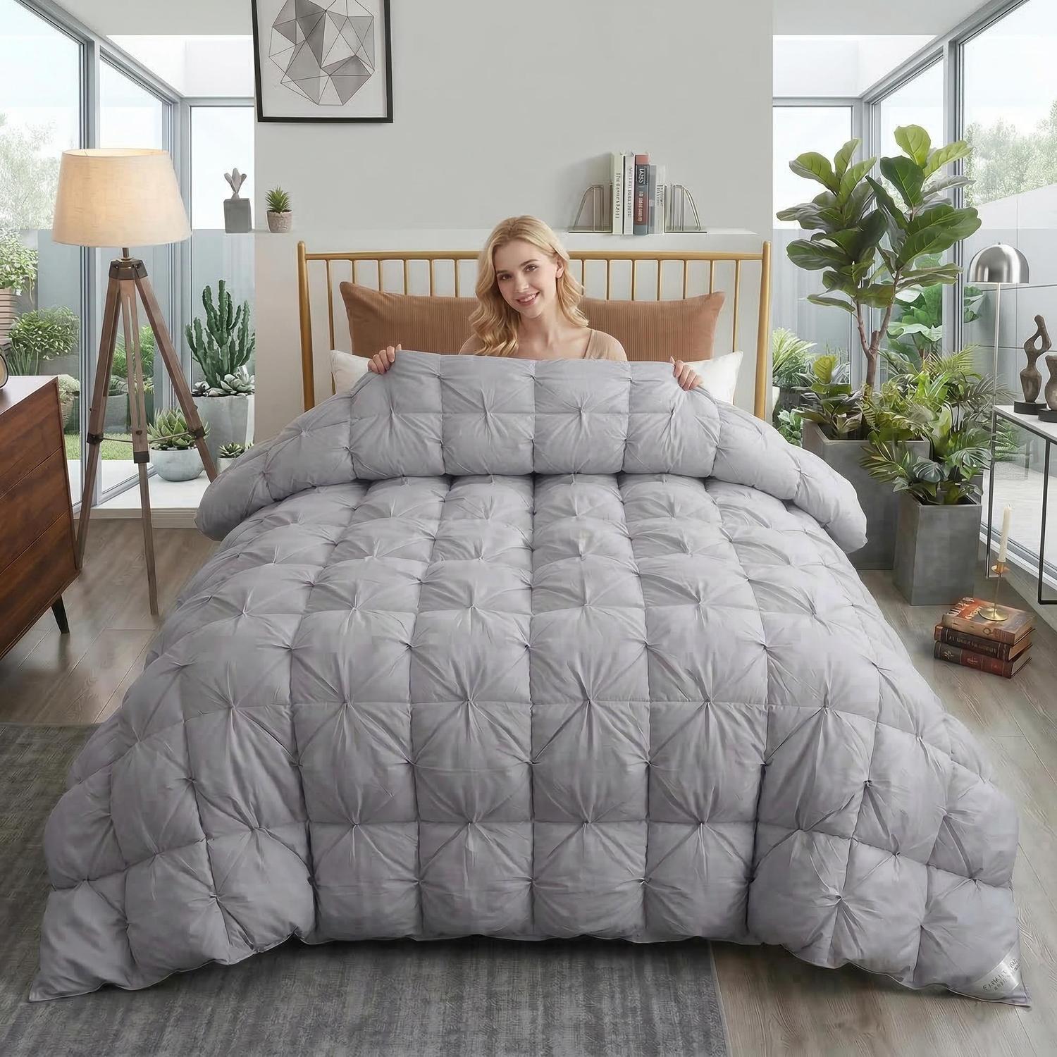 Woman holding a gray goose down comforter with a twist flower pattern in a bedroom.