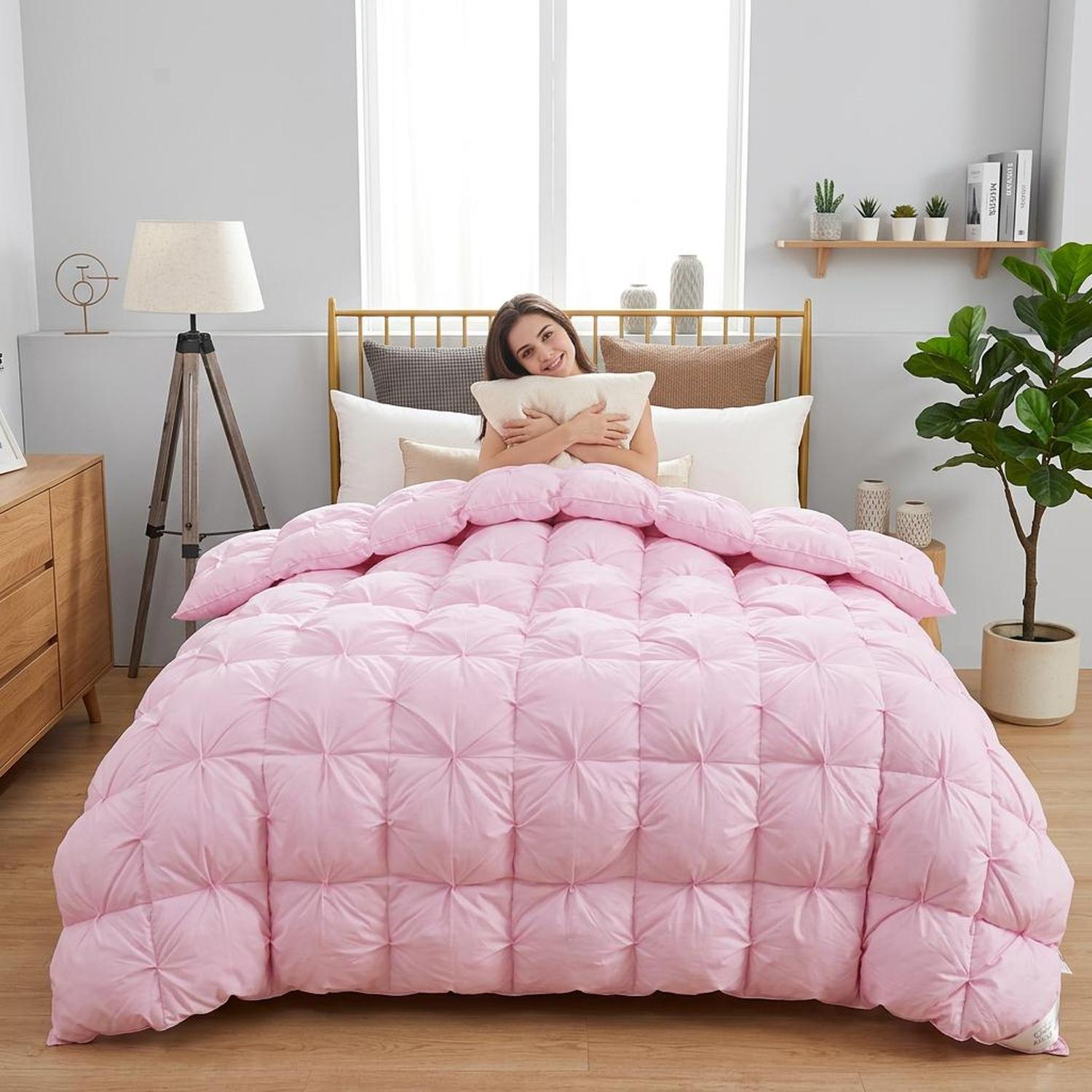 Smiling woman in bed with a pink goose down comforter featuring a twist flower design.