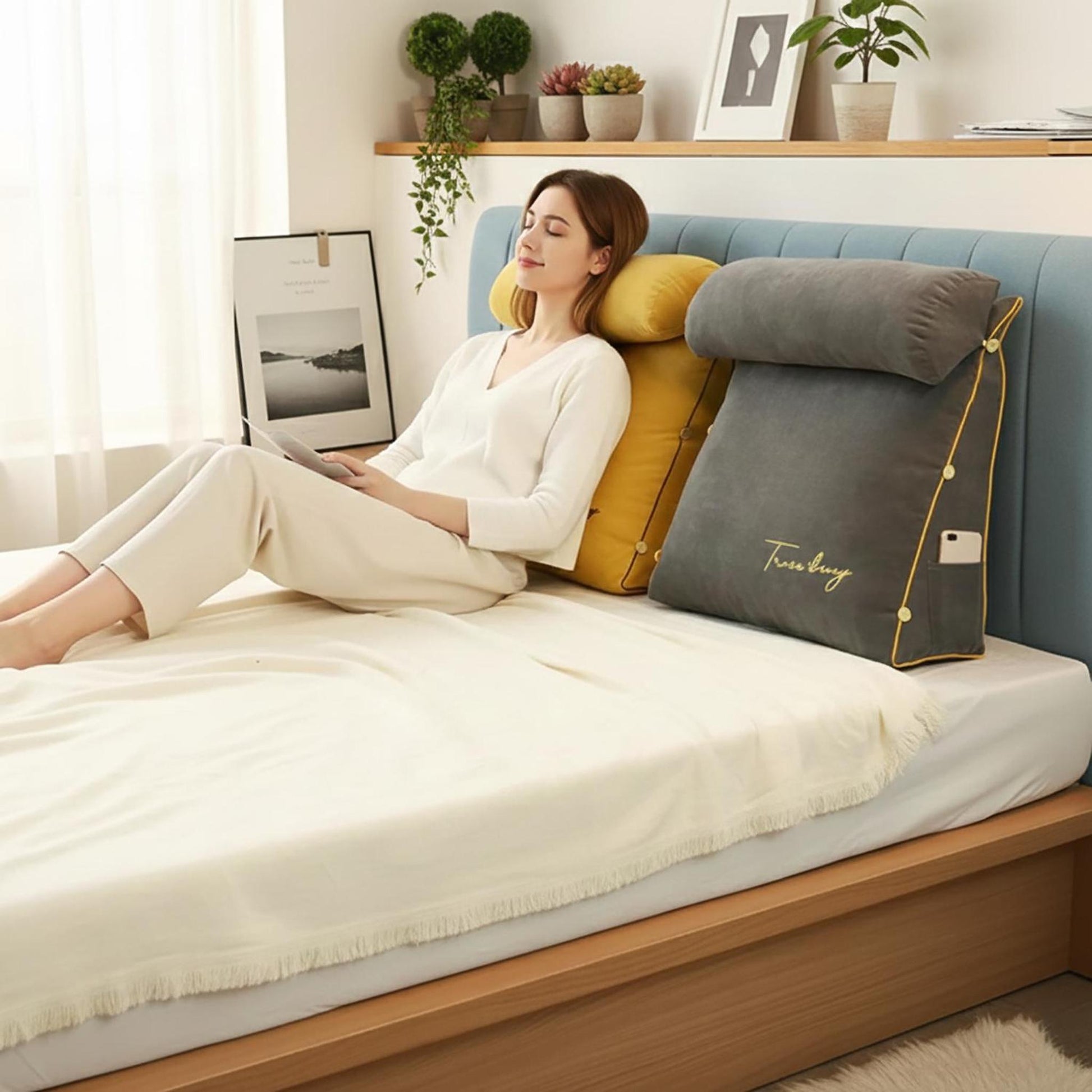 Woman relaxing on a bed with a gray ergonomic wedge lumbar support pillow and a yellow headrest.