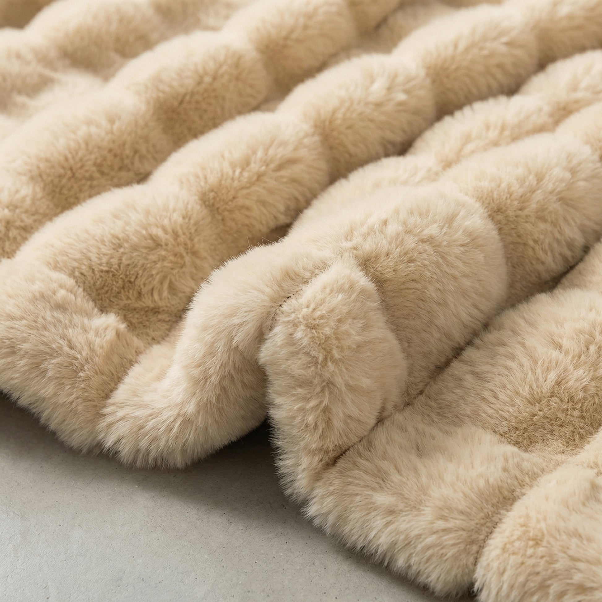 Close-up of a plush, beige faux fur striped throw blanket with a soft, textured design.