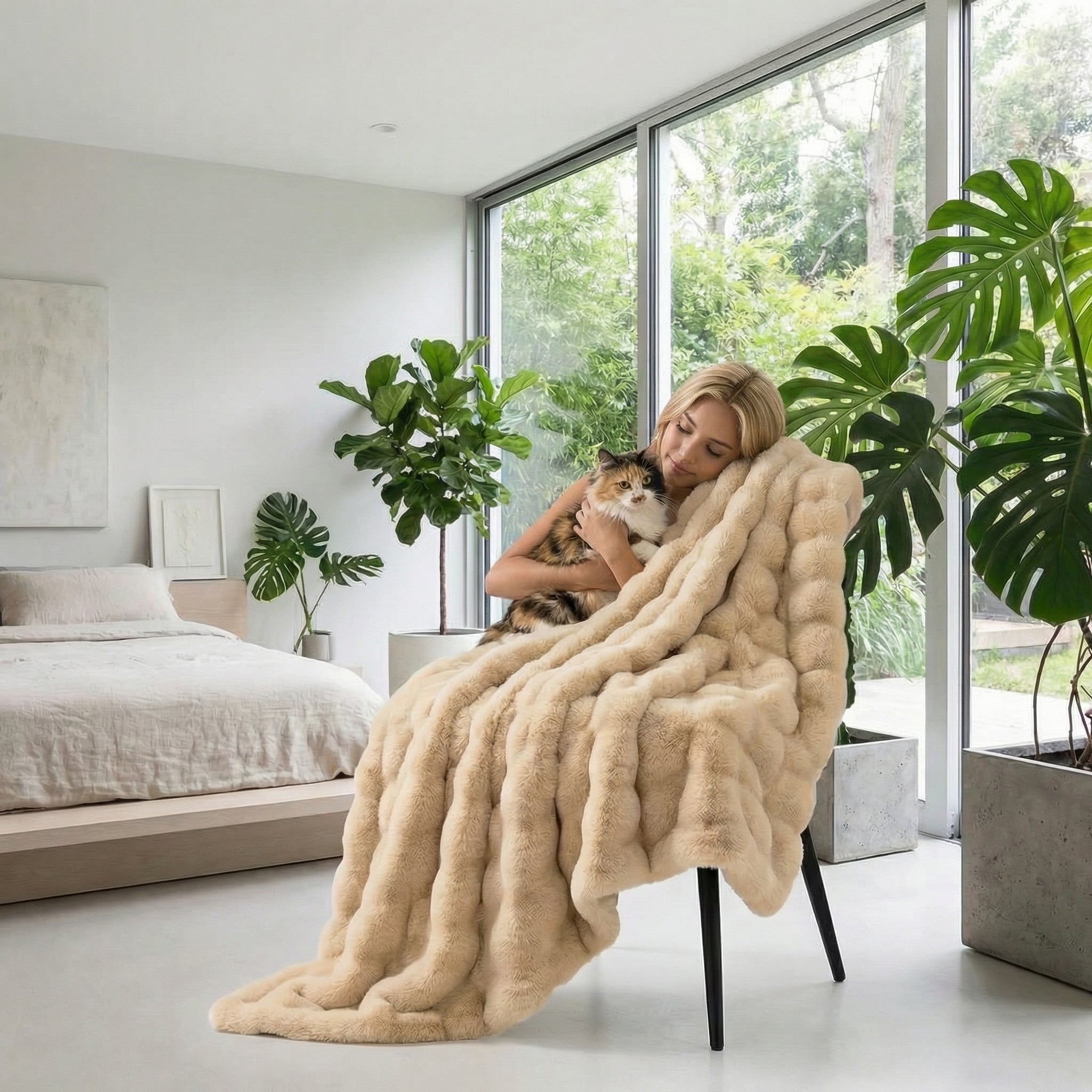 Blonde woman cuddling a calico cat under a plush, beige faux fur striped throw blanket in a modern room.