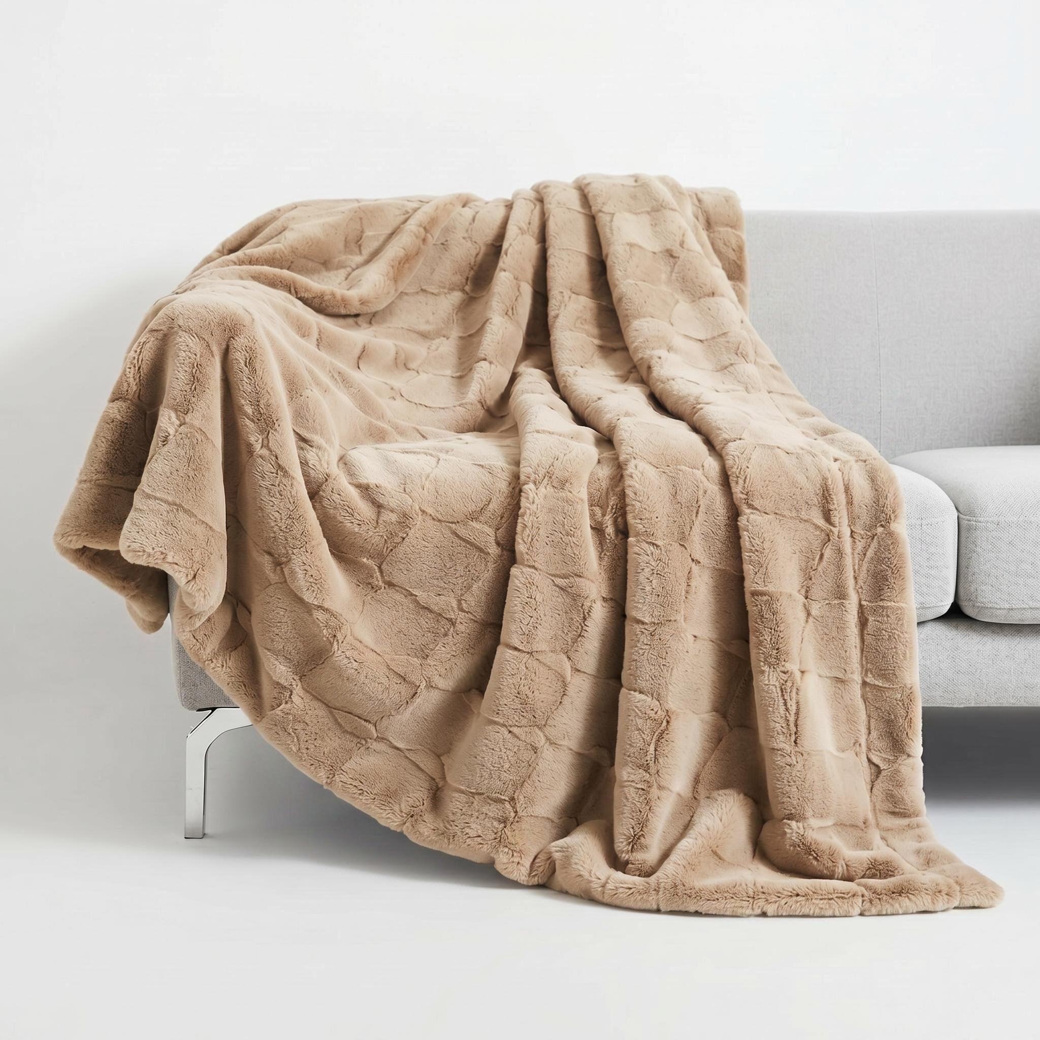 Soft, plush beige faux fur throw blanket draped elegantly over a grey sofa, showcasing its rich texture.