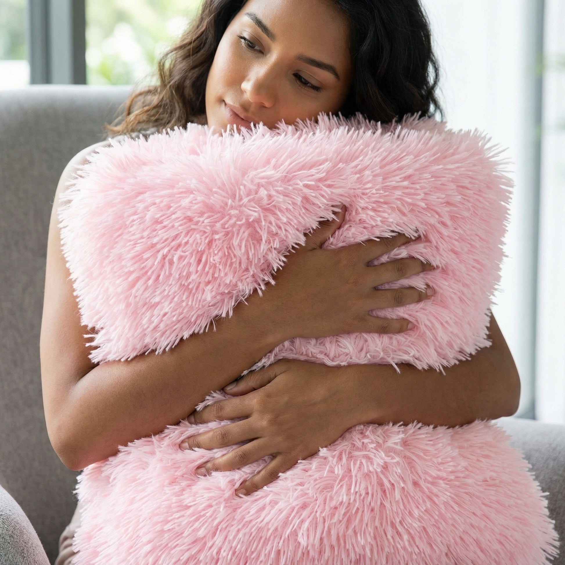 Woman hugging a soft, fluffy pink faux microfiber blanket or pillow, showcasing its gentle texture.