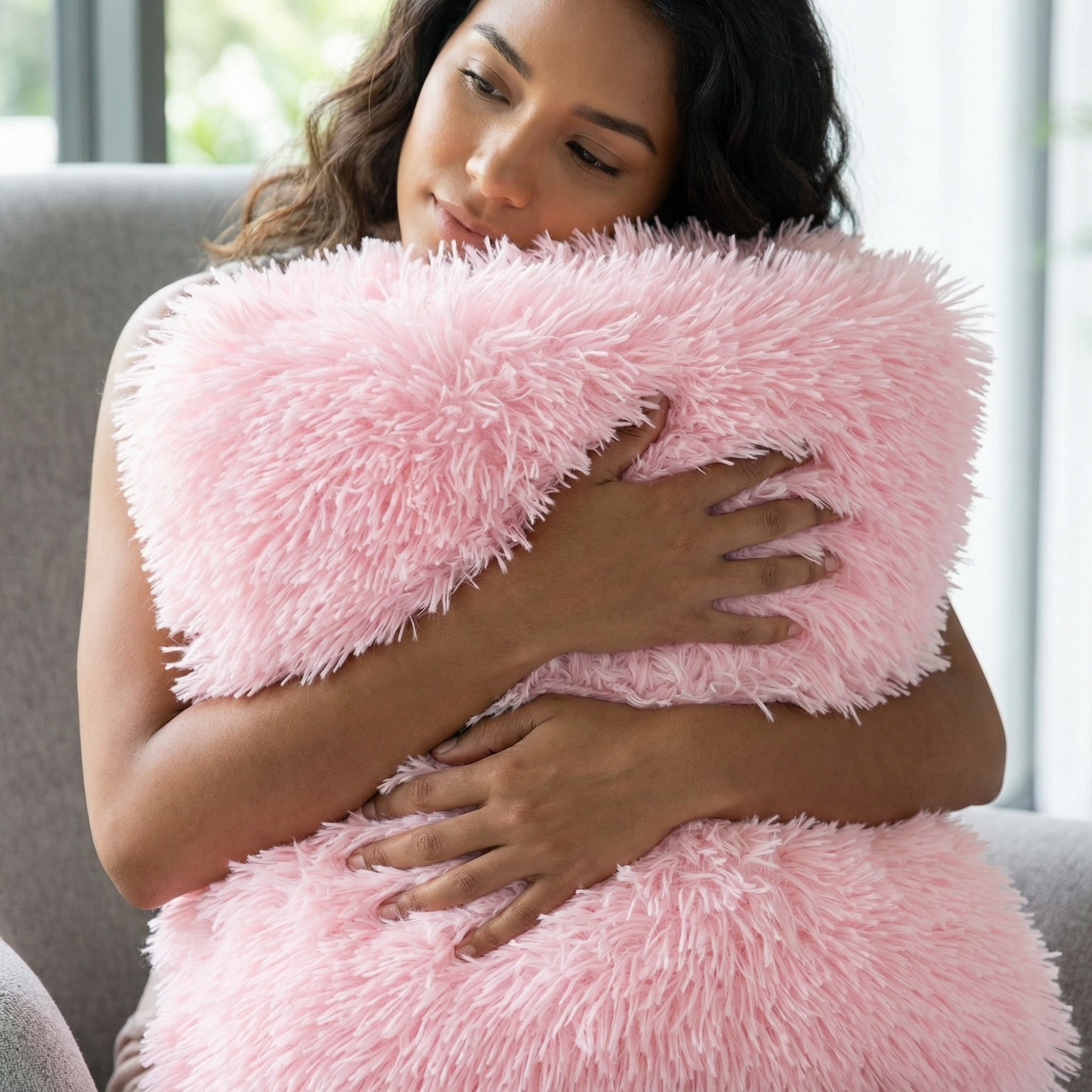 Woman hugging a soft, fluffy pink faux microfiber blanket or pillow, showcasing its gentle texture.