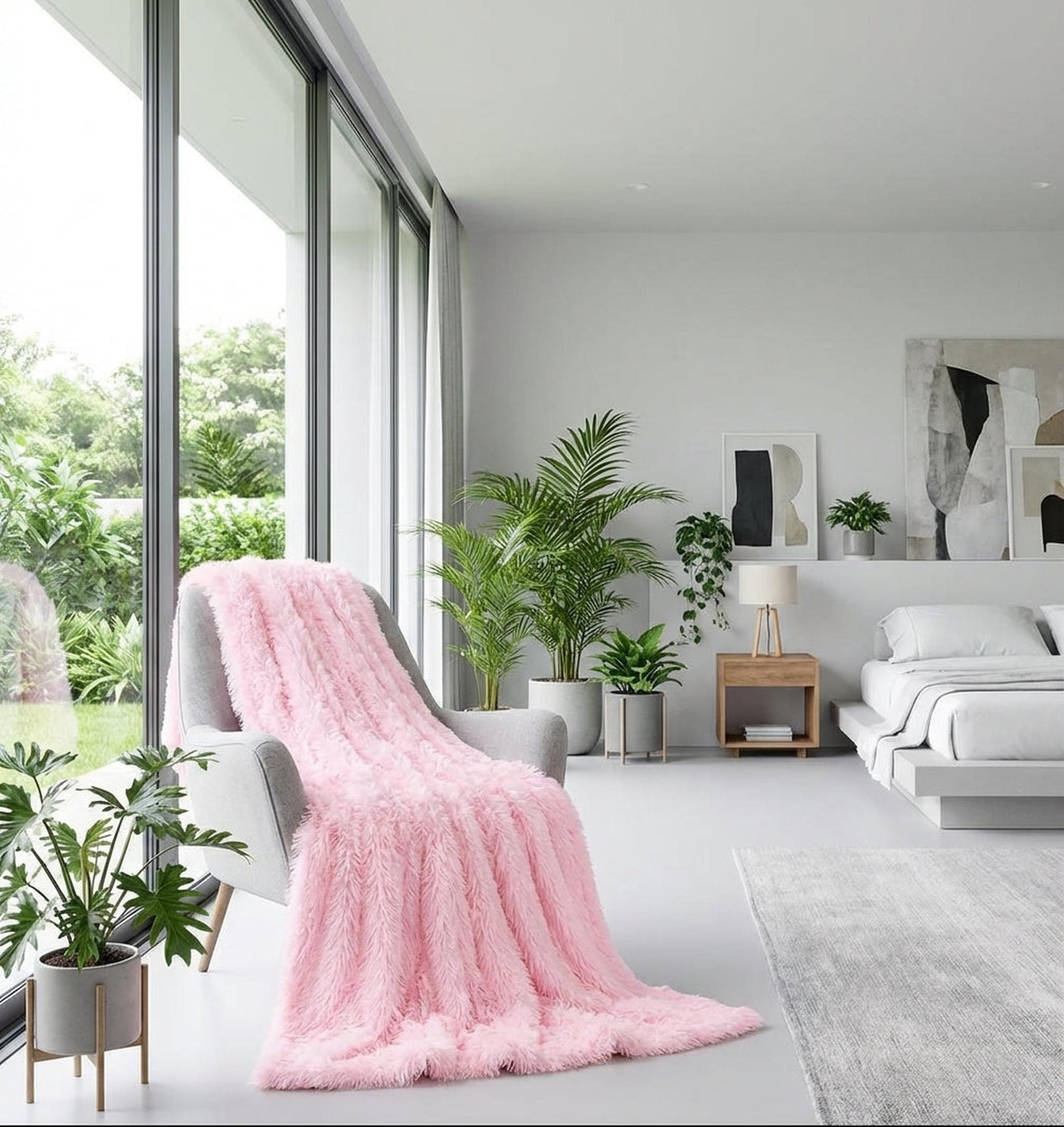 Soft pink faux microfiber coral fleece blanket draped over a gray armchair in a modern bedroom.