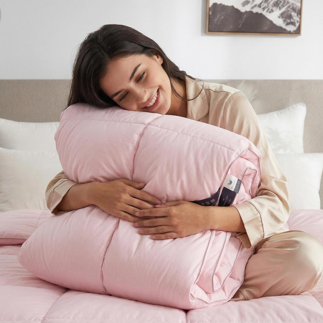 Smiling woman in pajamas on a bed with a soft pink goose down cotton quilt comforter and matching pillow.