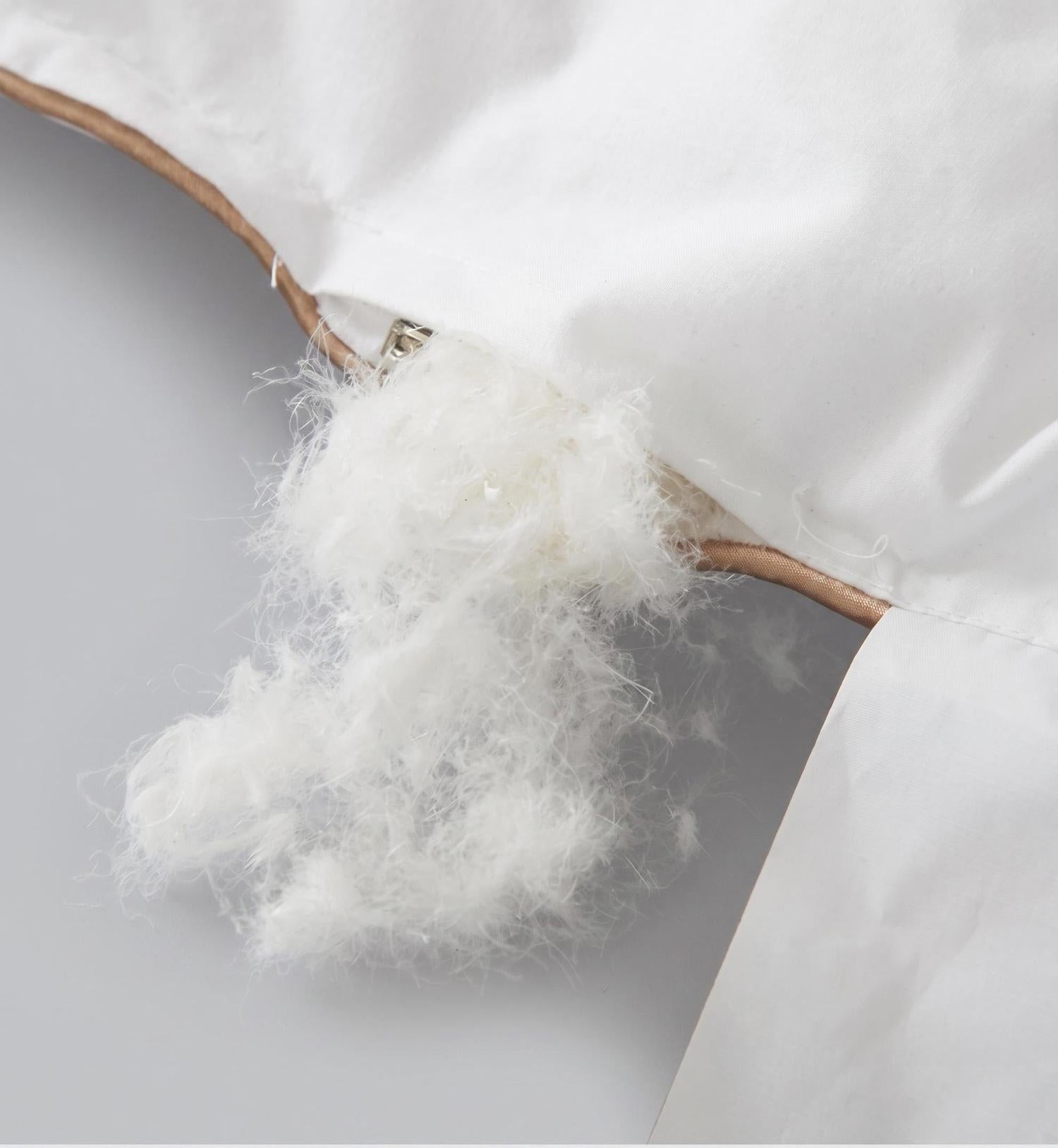 White cotton quilt comforter showing soft white goose down filling spilling from a zippered opening.