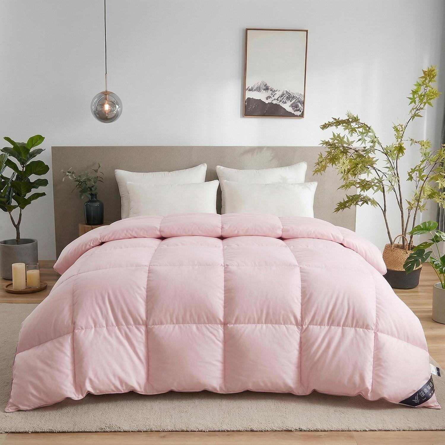 Pink feather goose down cotton quilt comforter with square baffling on a bed, surrounded by plants.