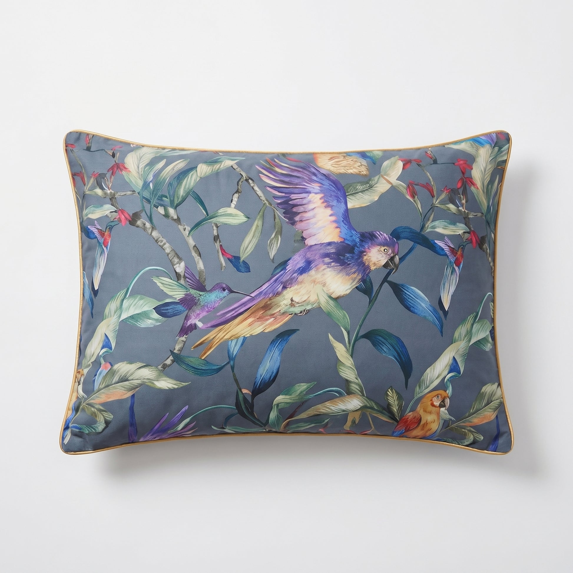 Rectangular pillow with vibrant painterly florals, tropical birds, and a gold sateen trim on a blue-grey background.