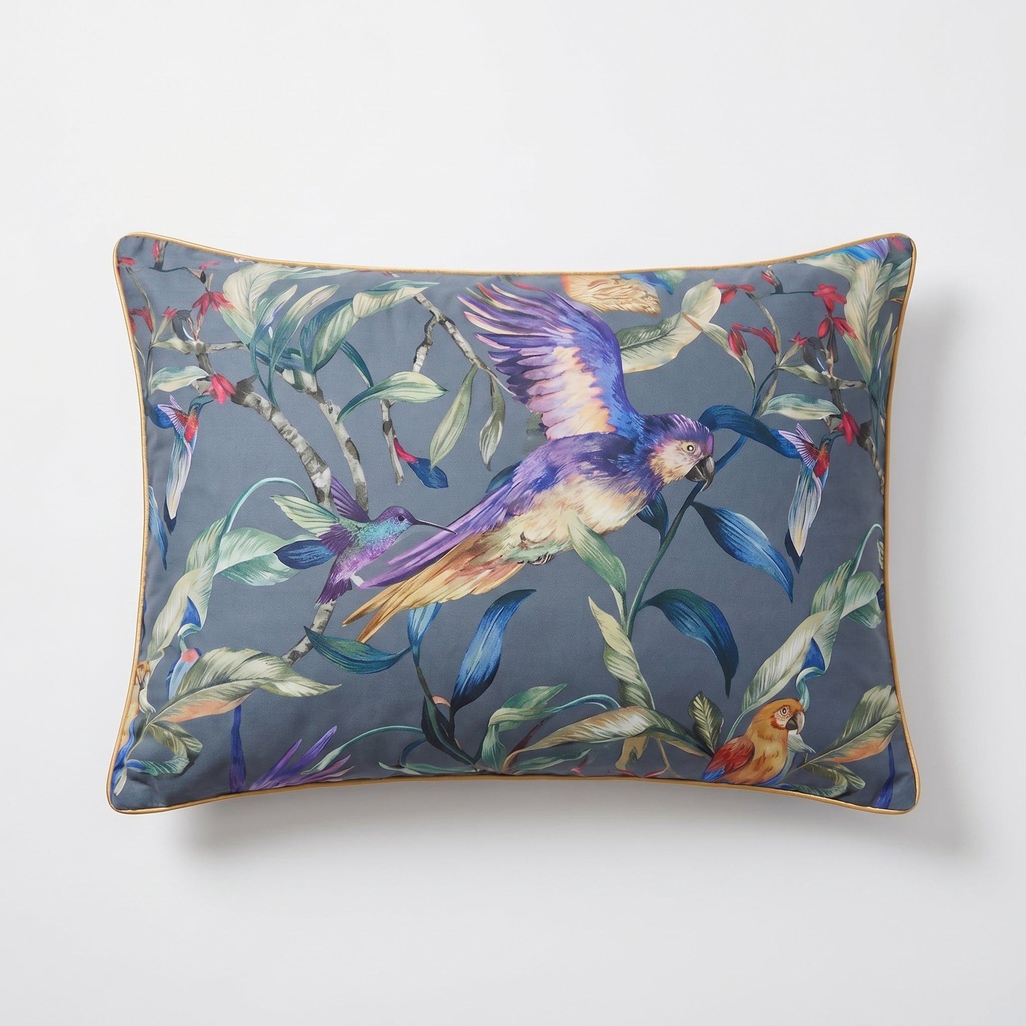 Rectangular pillow with vibrant painterly florals, tropical birds, and a gold sateen trim on a blue-grey background.