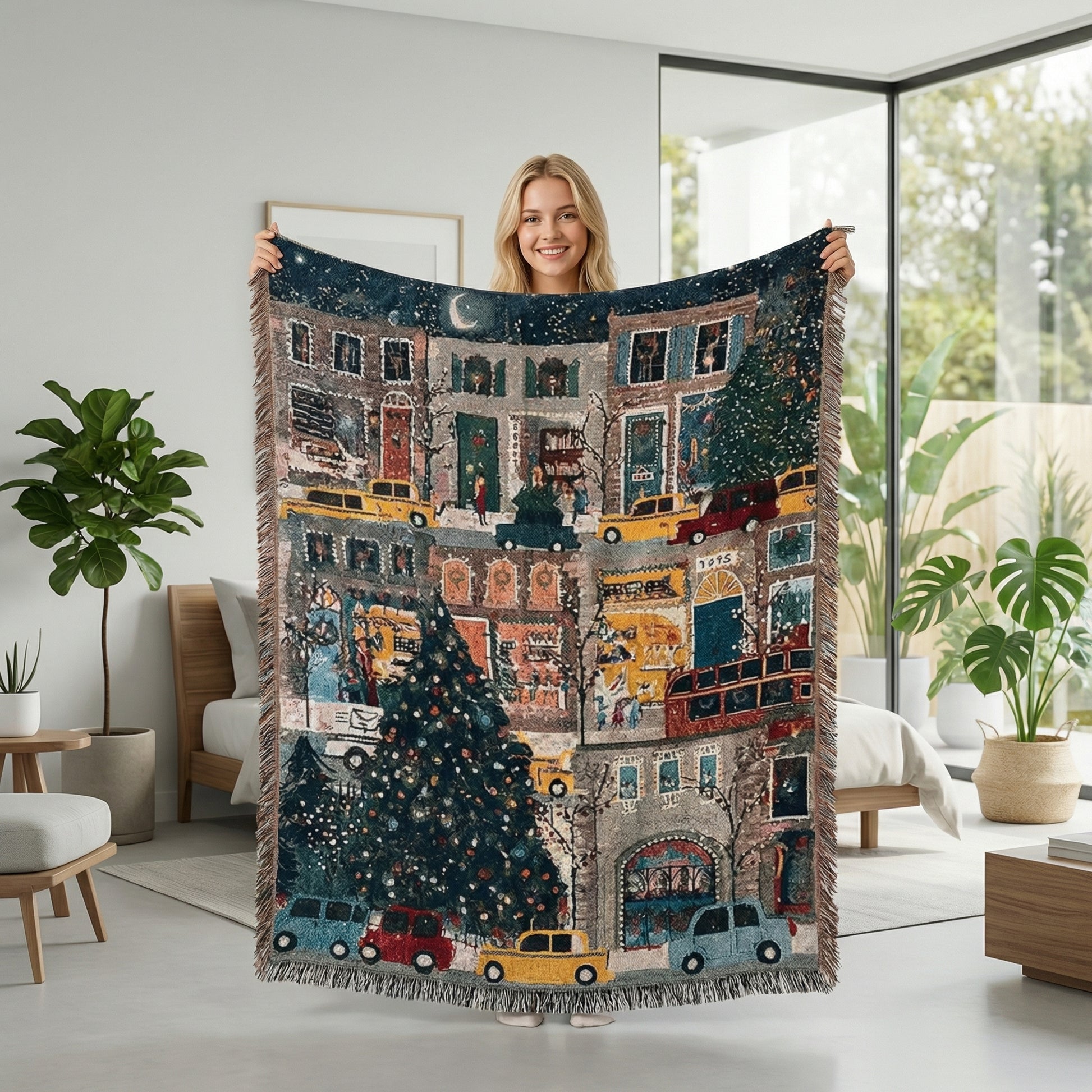 Smiling woman holding a large, festive Christmas knitted throw blanket with a colorful city street scene and fringe accents.