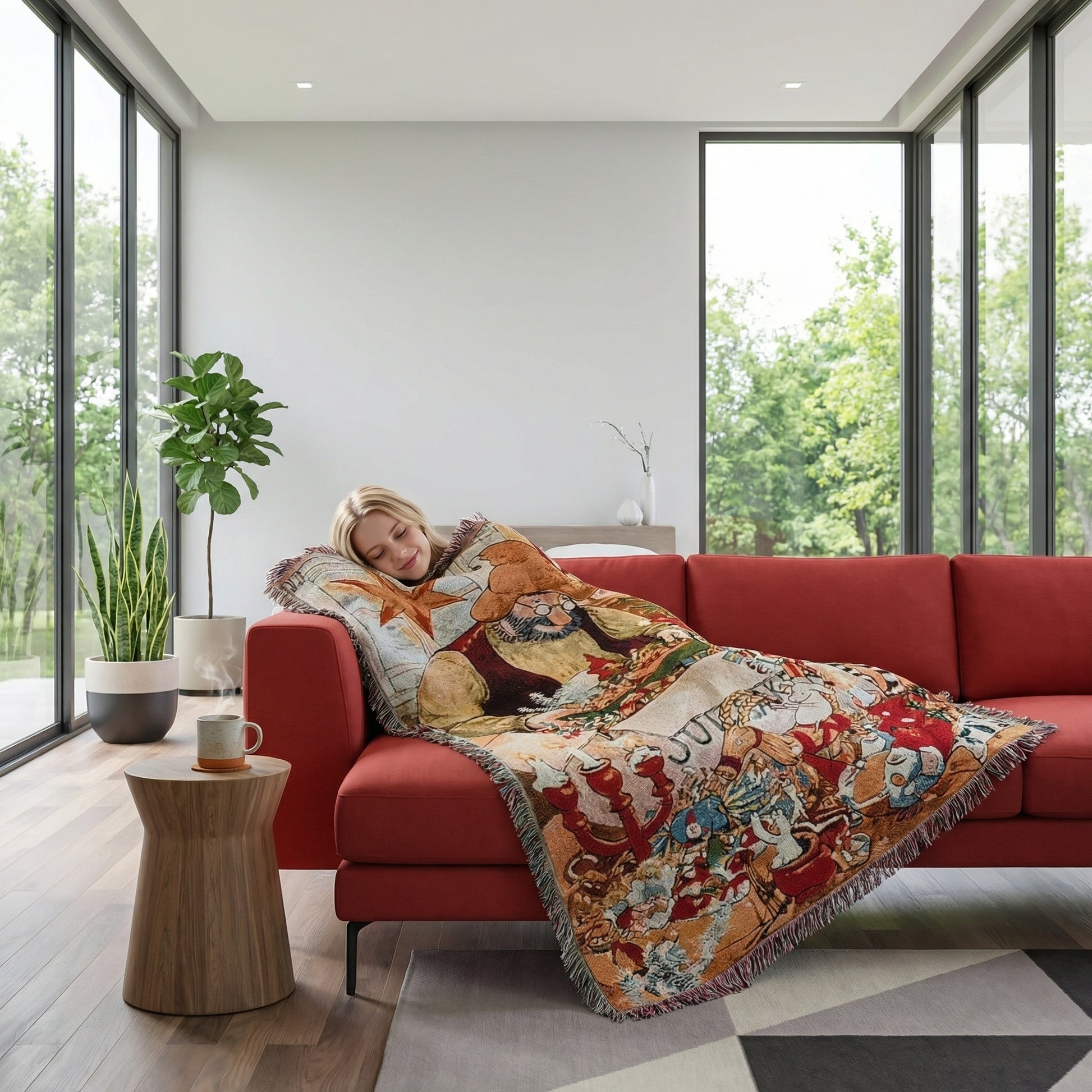 Woman sleeping on a red sofa, covered by a festive Christmas knitted throw blanket with fringe accents.