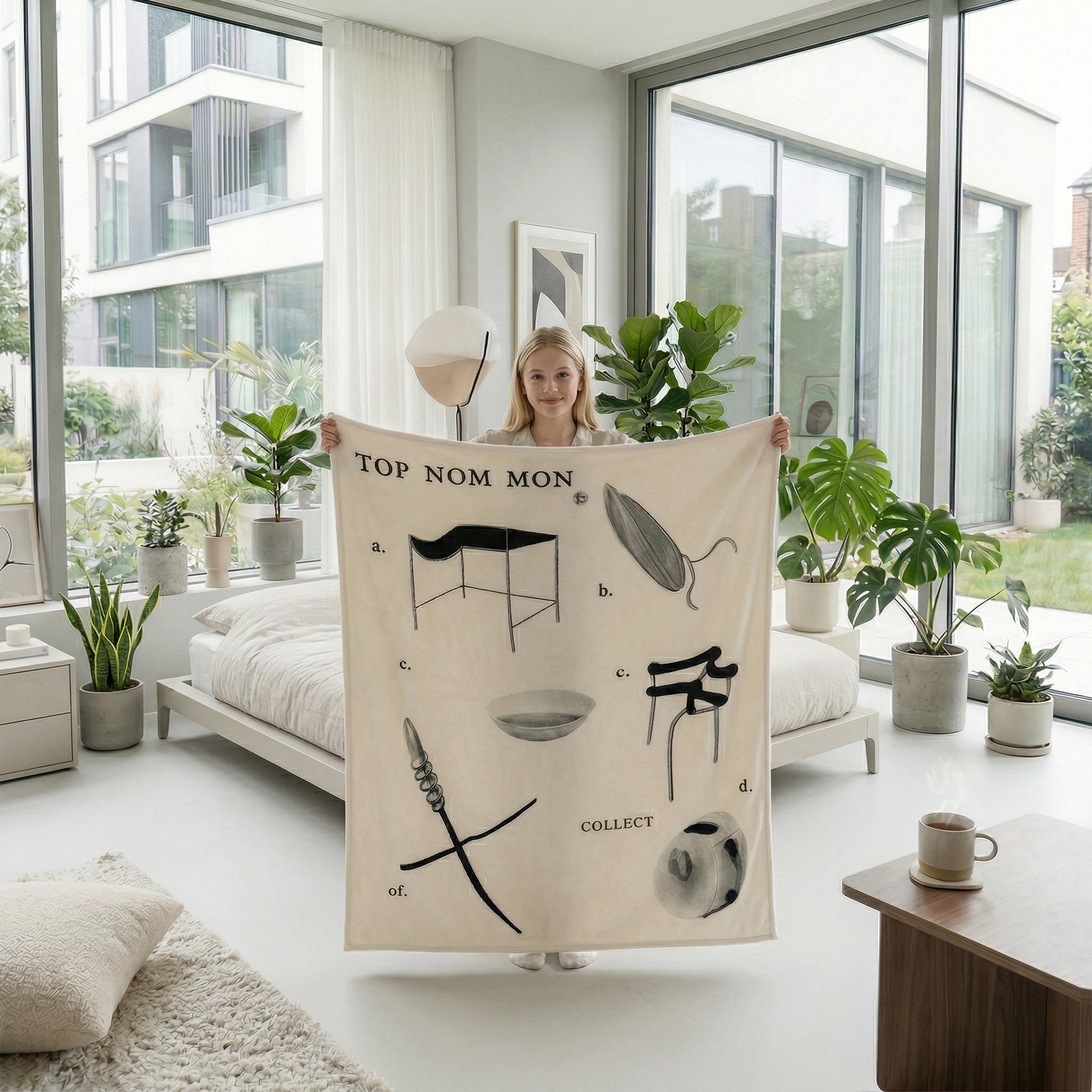 Young woman holding a beige flannel throw blanket with black abstract designs in a bright bedroom.