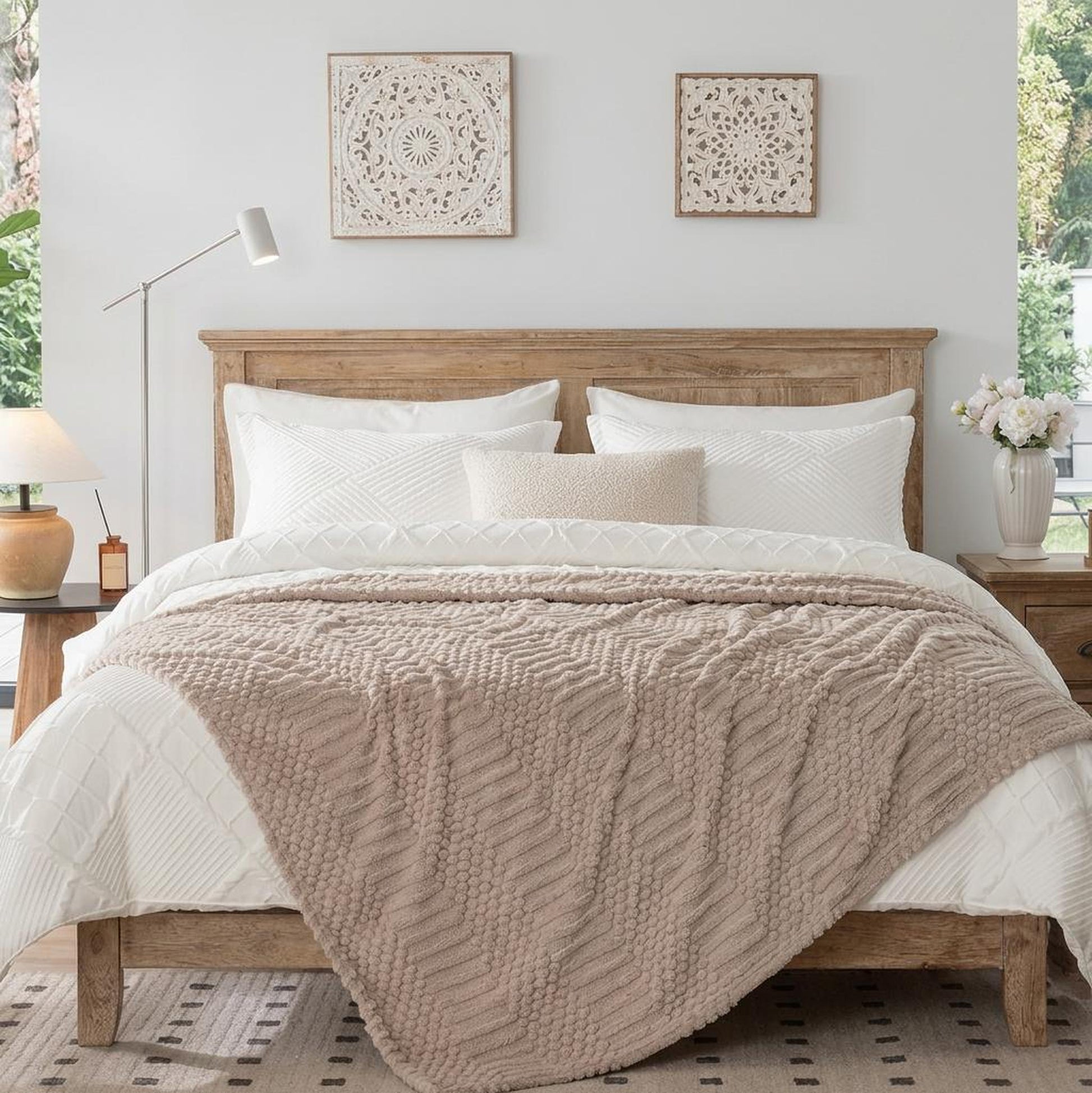Soft beige fleece throw blanket with a textured chevron pattern draped over a white bed in a cozy bedroom.