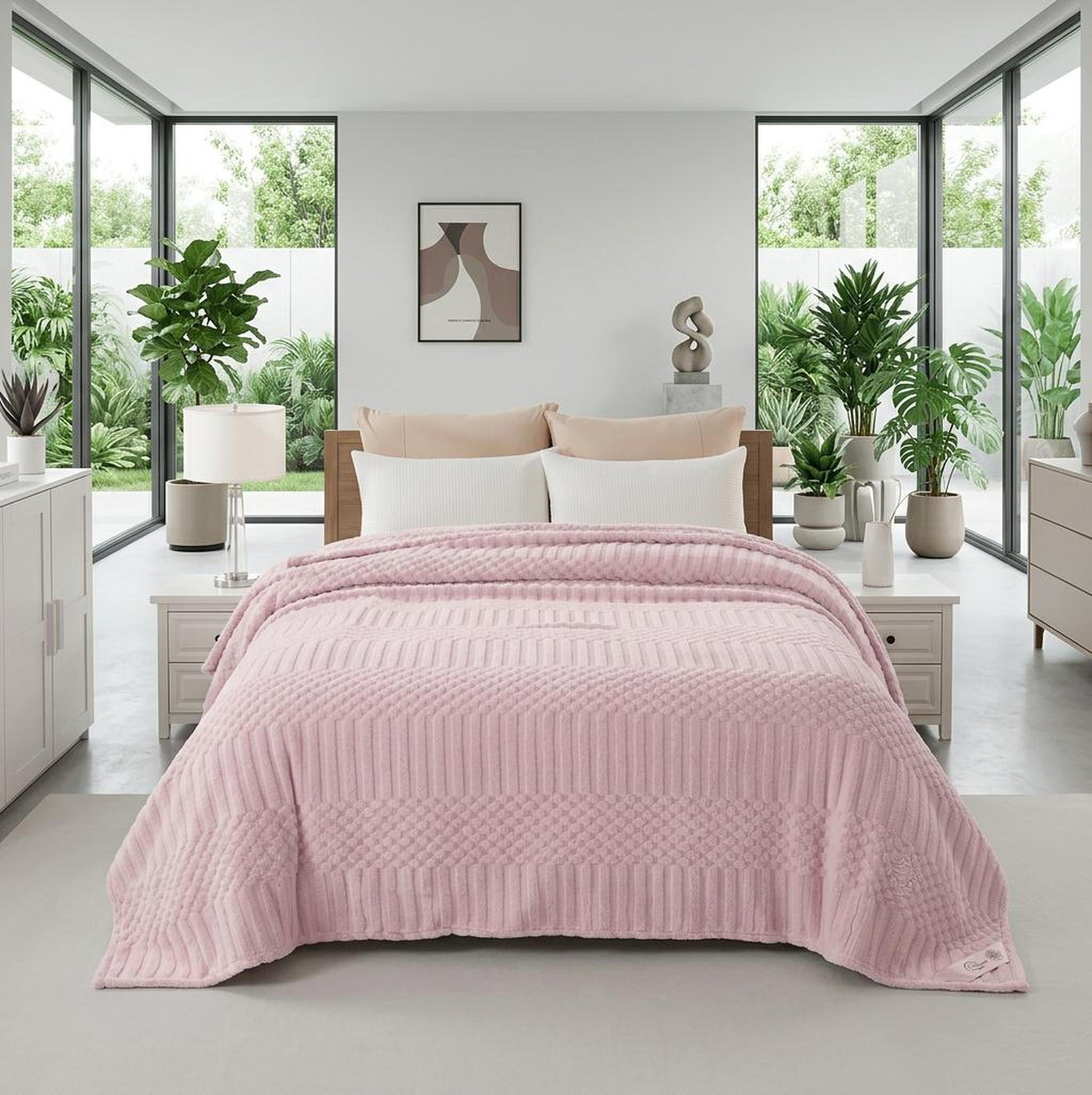 Soft pink fleece throw blanket with textured geometric patterns on a bed in a bright bedroom.