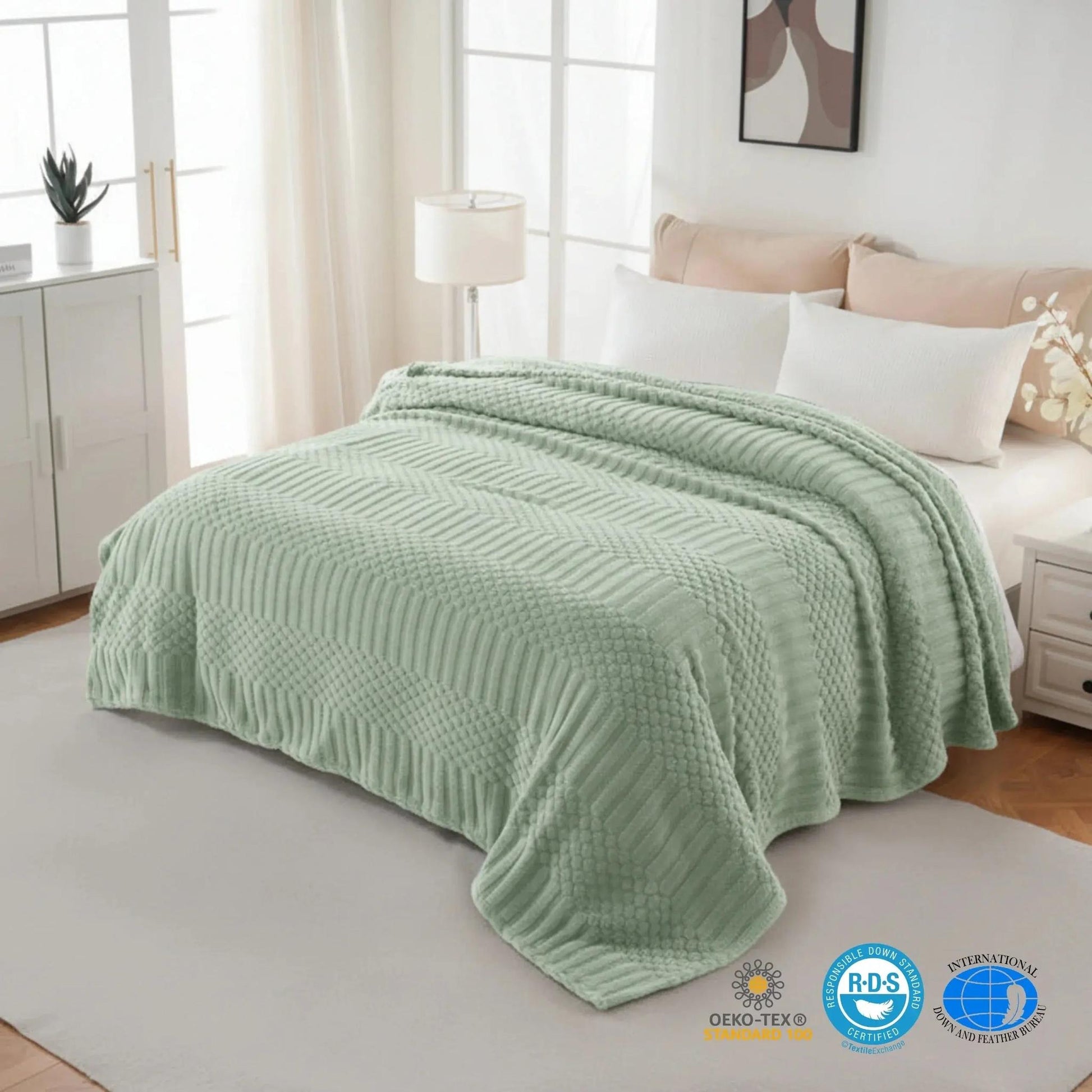 Soft sage green 50x70 inch fleece throw blanket with textured chevron and dot patterns draped on a bed.