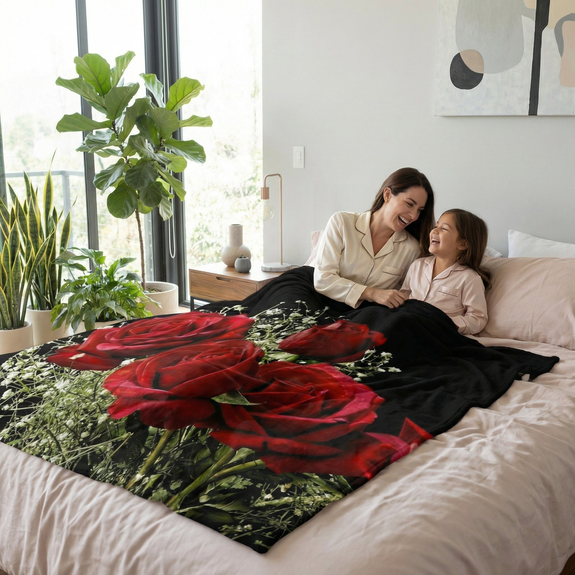Black fleece blanket with vibrant 3D red roses and babysbreath, draped on a bed with a mother and child.