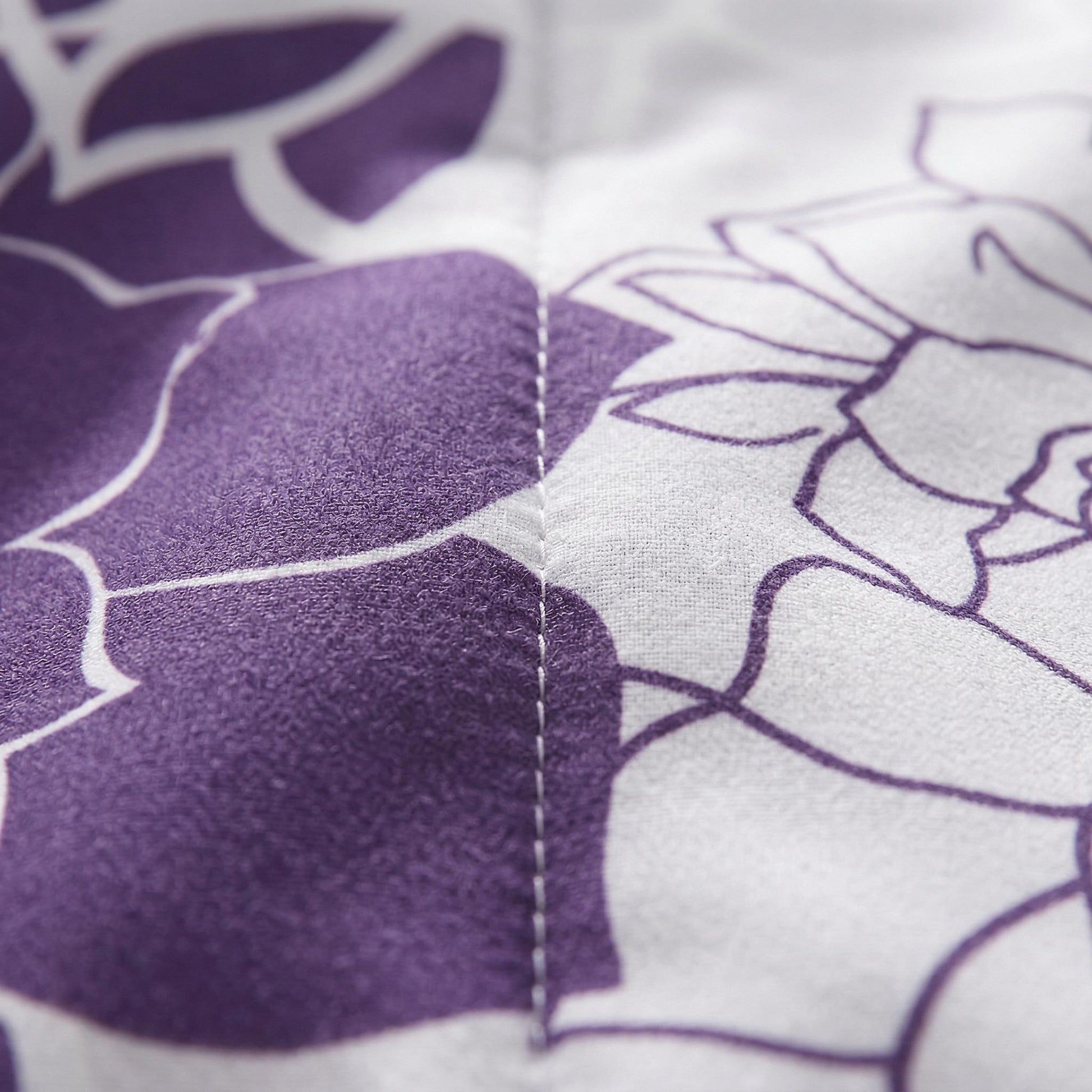 Close-up of a soft, reversible microfiber floral bedding set with purple and white pinch pleat design.