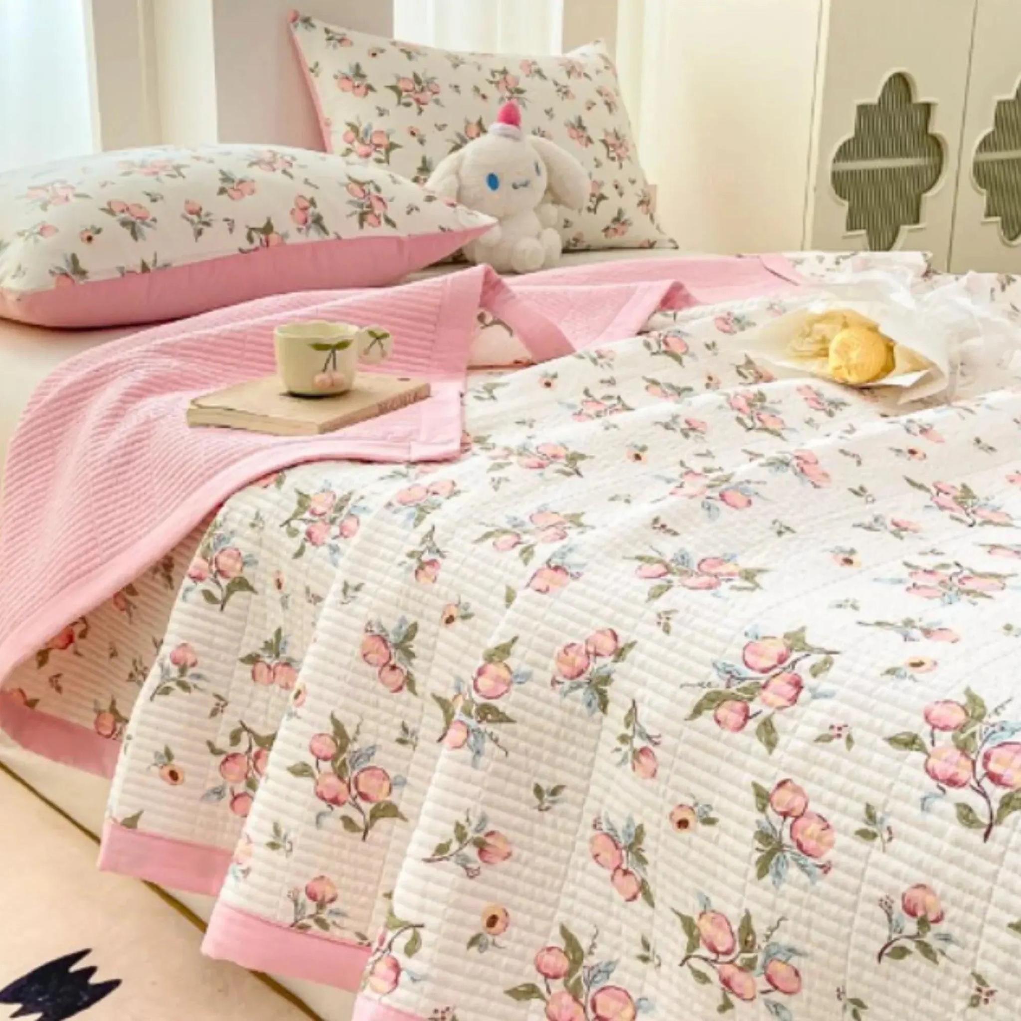 White microfiber quilt with pink floral pattern, pink border, and matching pillowcases on a bed.
