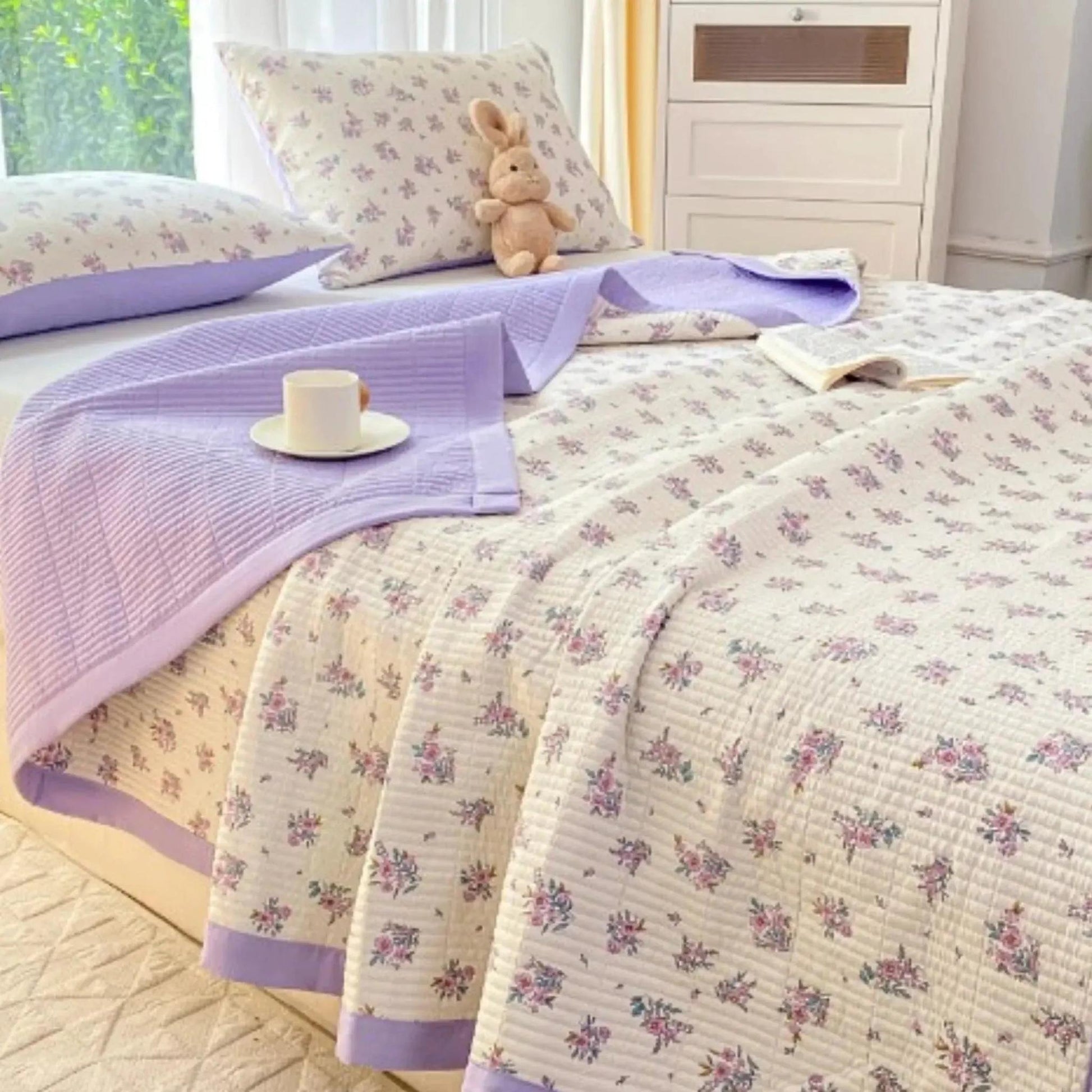 Floral microfiber quilt bedding set with lavender trim, two pillows, and a matching throw.