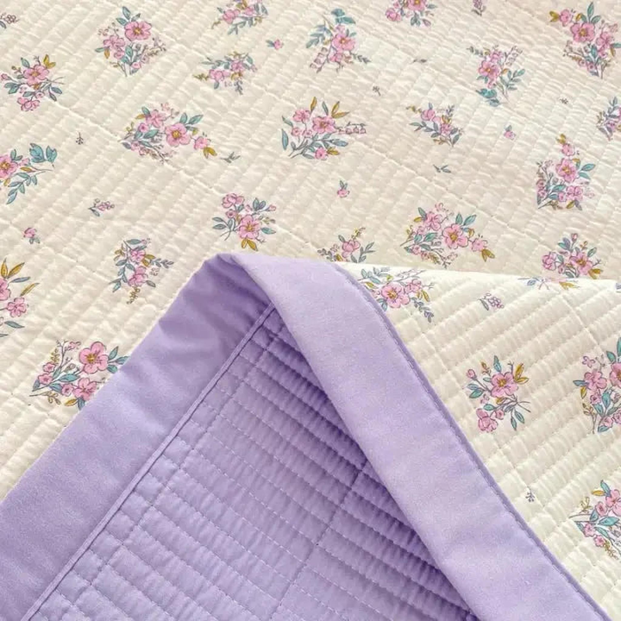 Floral microfiber quilt bedding set with pink flowers on cream and a solid lavender reverse.