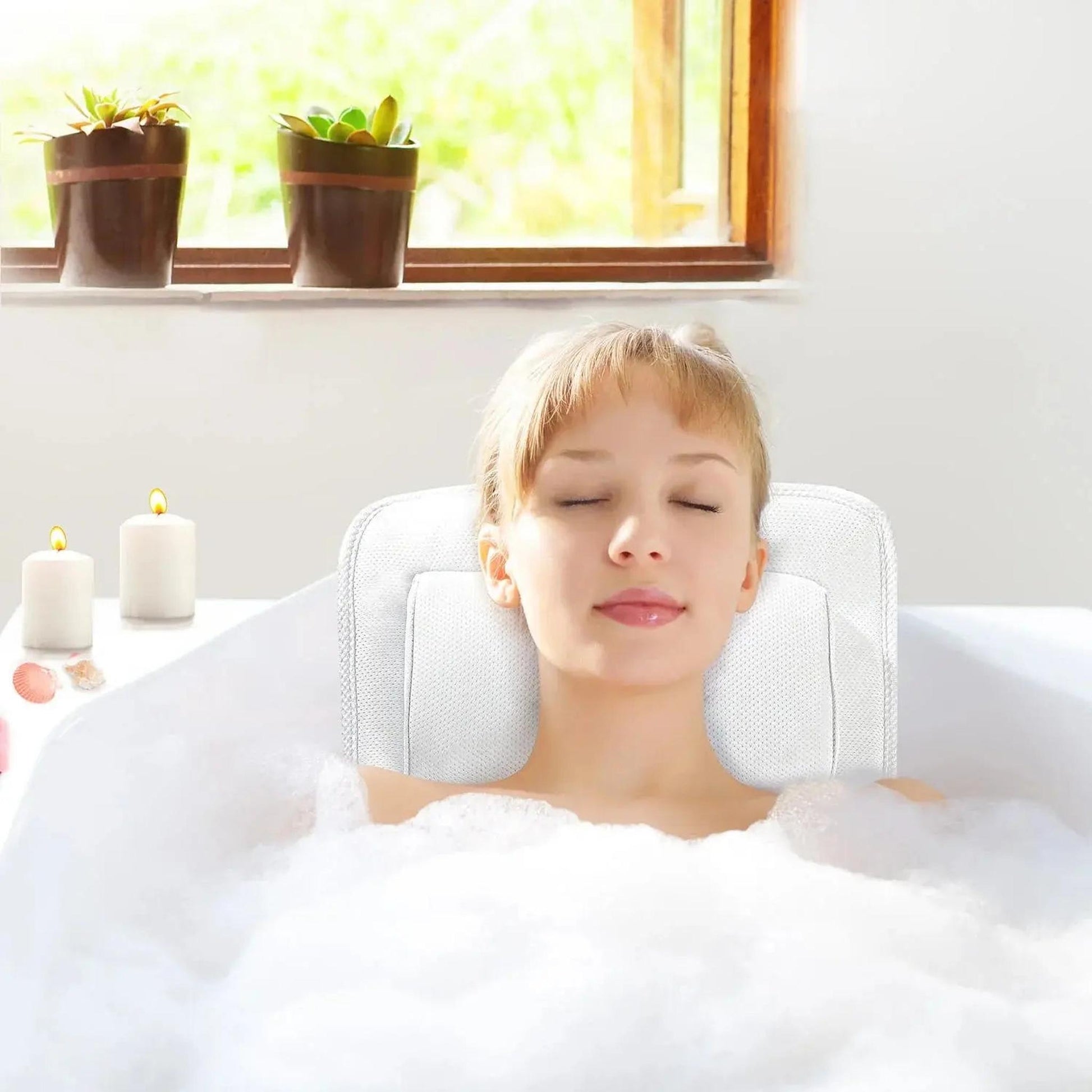 Woman relaxing in a bubble bath with her head resting on a white mesh full body bath pillow.