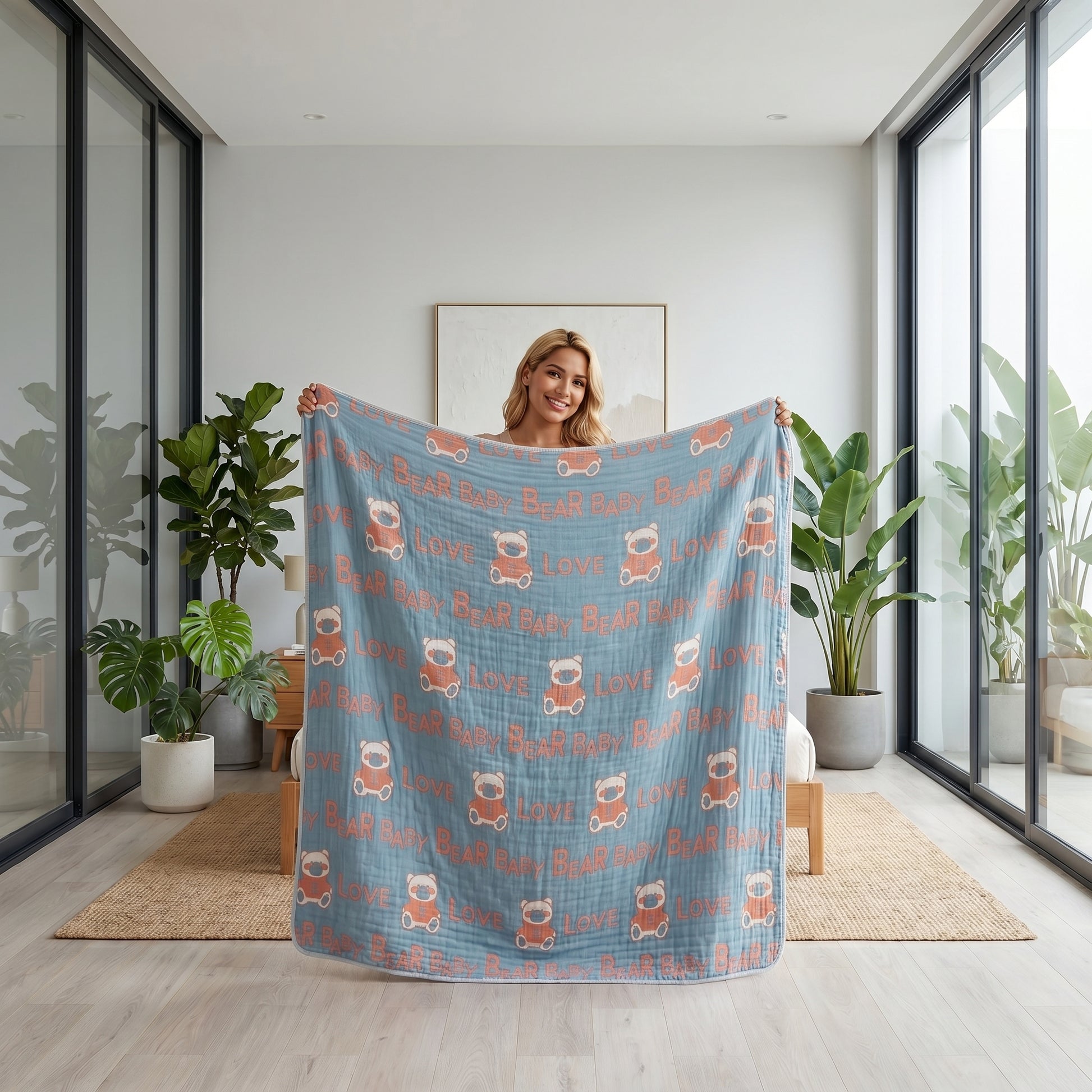 Smiling woman holding a blue 6-layer cotton gauze blanket with orange bear and "LOVE" pattern.