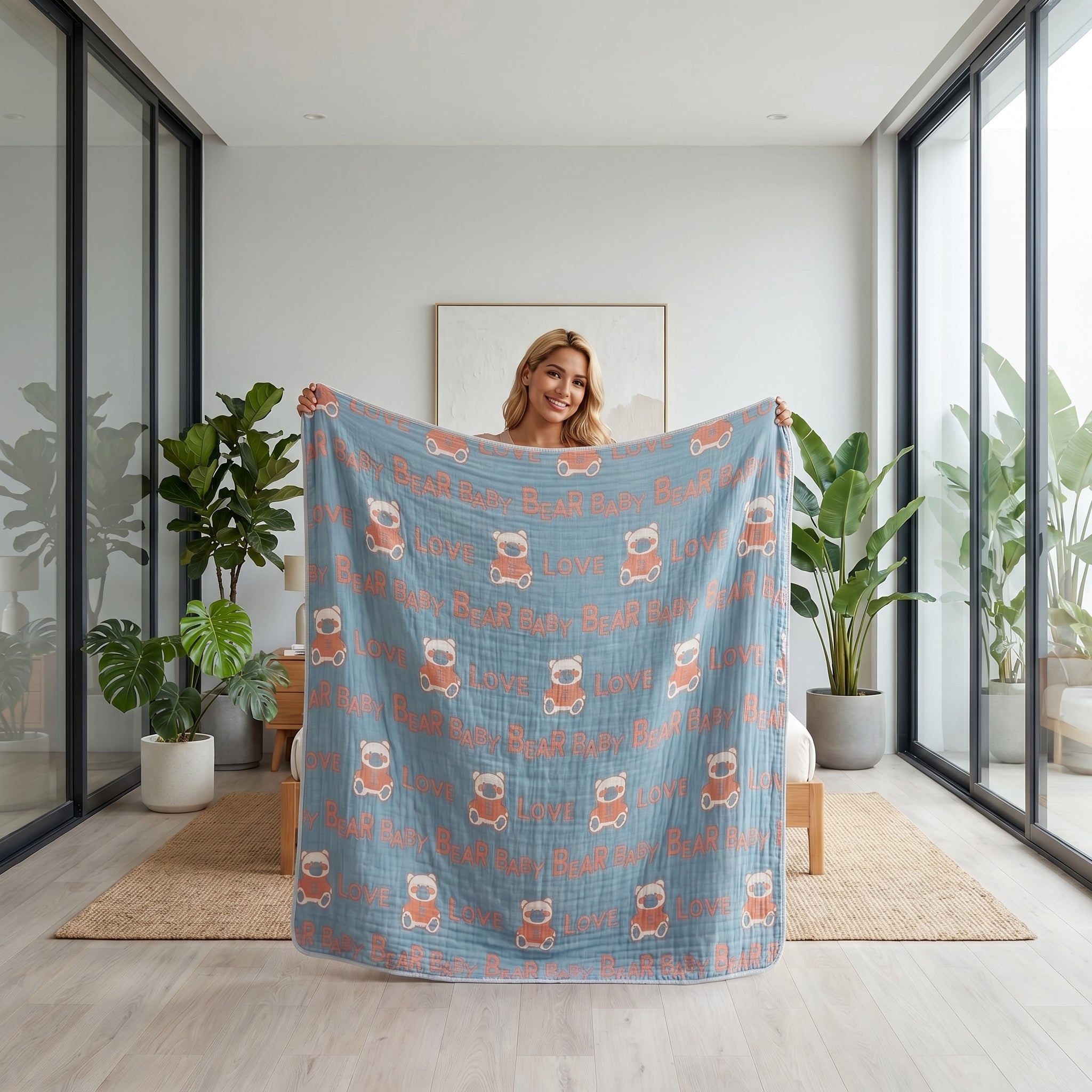 Smiling woman holding a blue 6-layer cotton gauze blanket with orange bear and "LOVE" pattern.