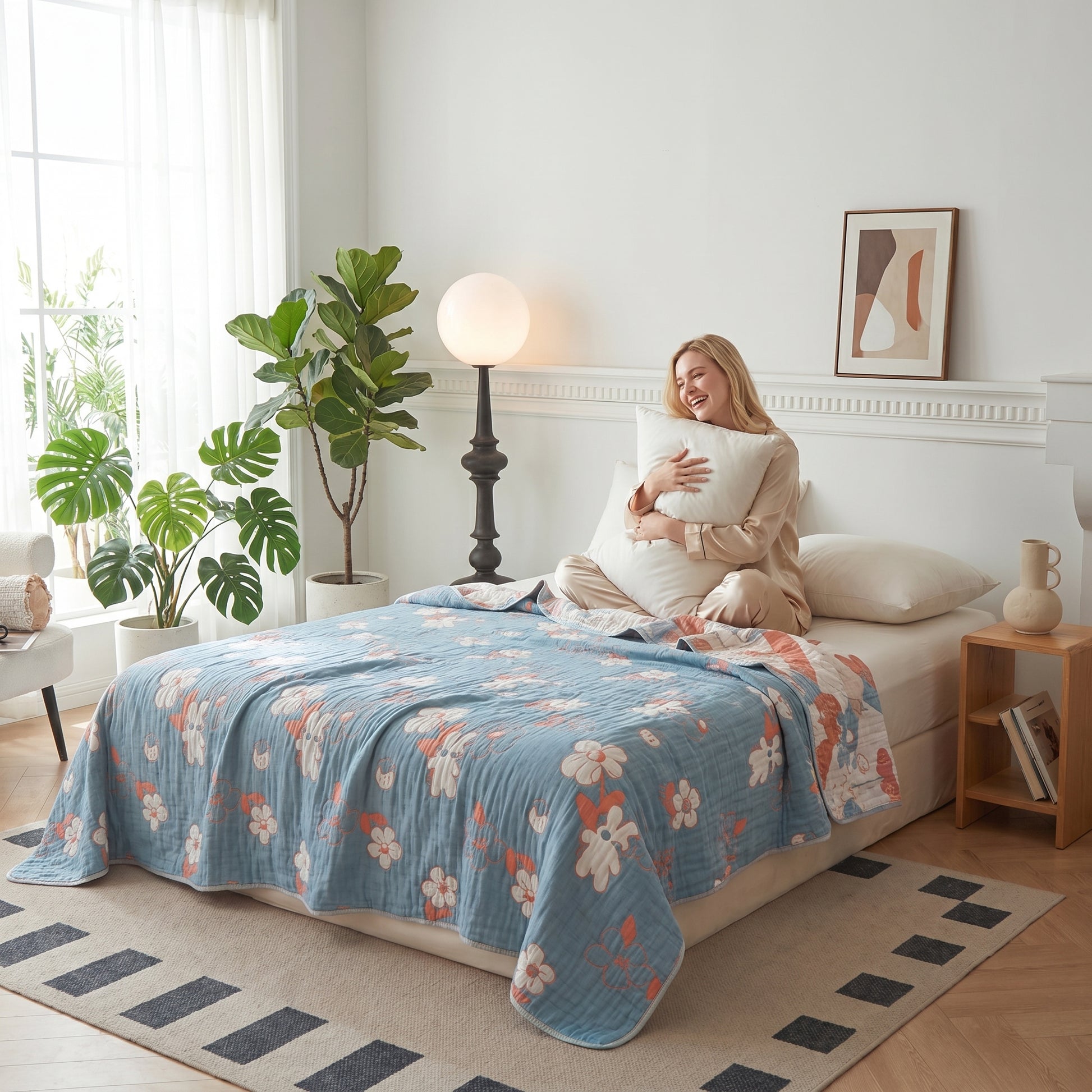 Woman on bed with a reversible blue and coral floral 6-layer cotton gauze blanket.